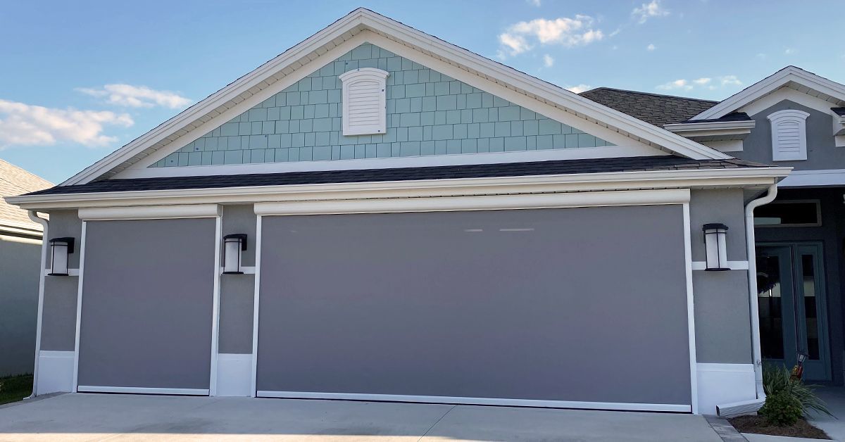 Suburban house facade with gray garage doors and light blue gable siding