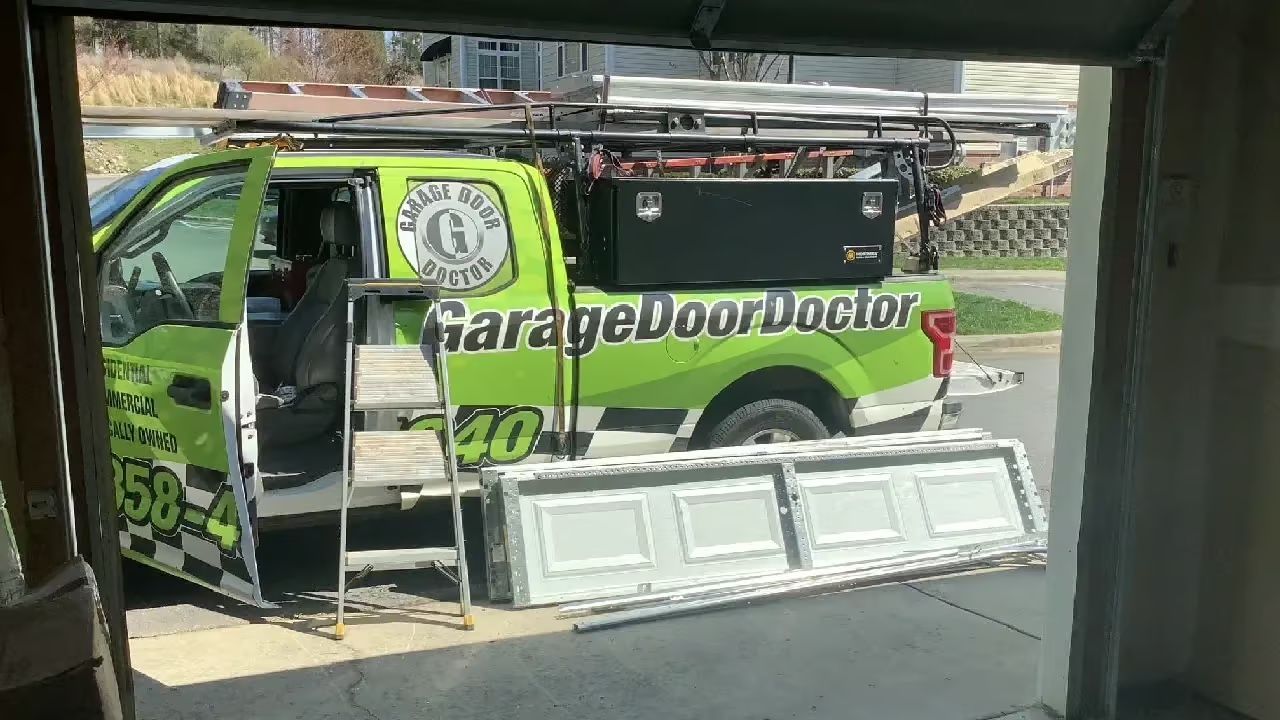 A Garage Door Doctor truck with a new garage door in front of an open garage.