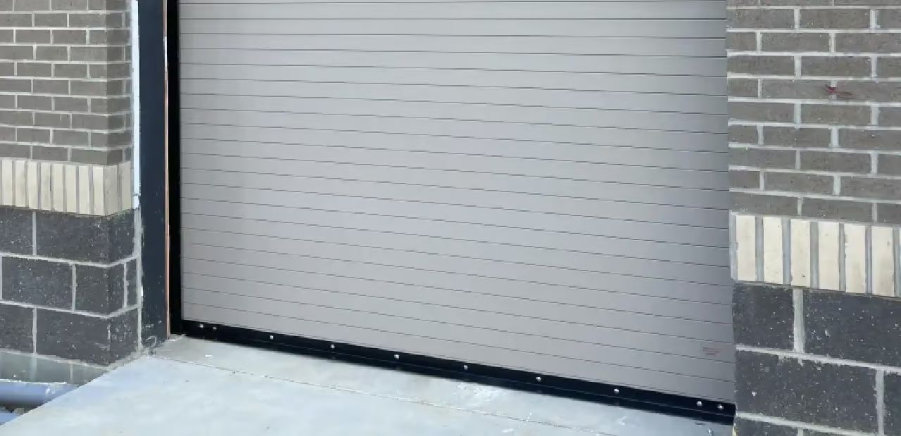 Gray closed garage door between brick walls.