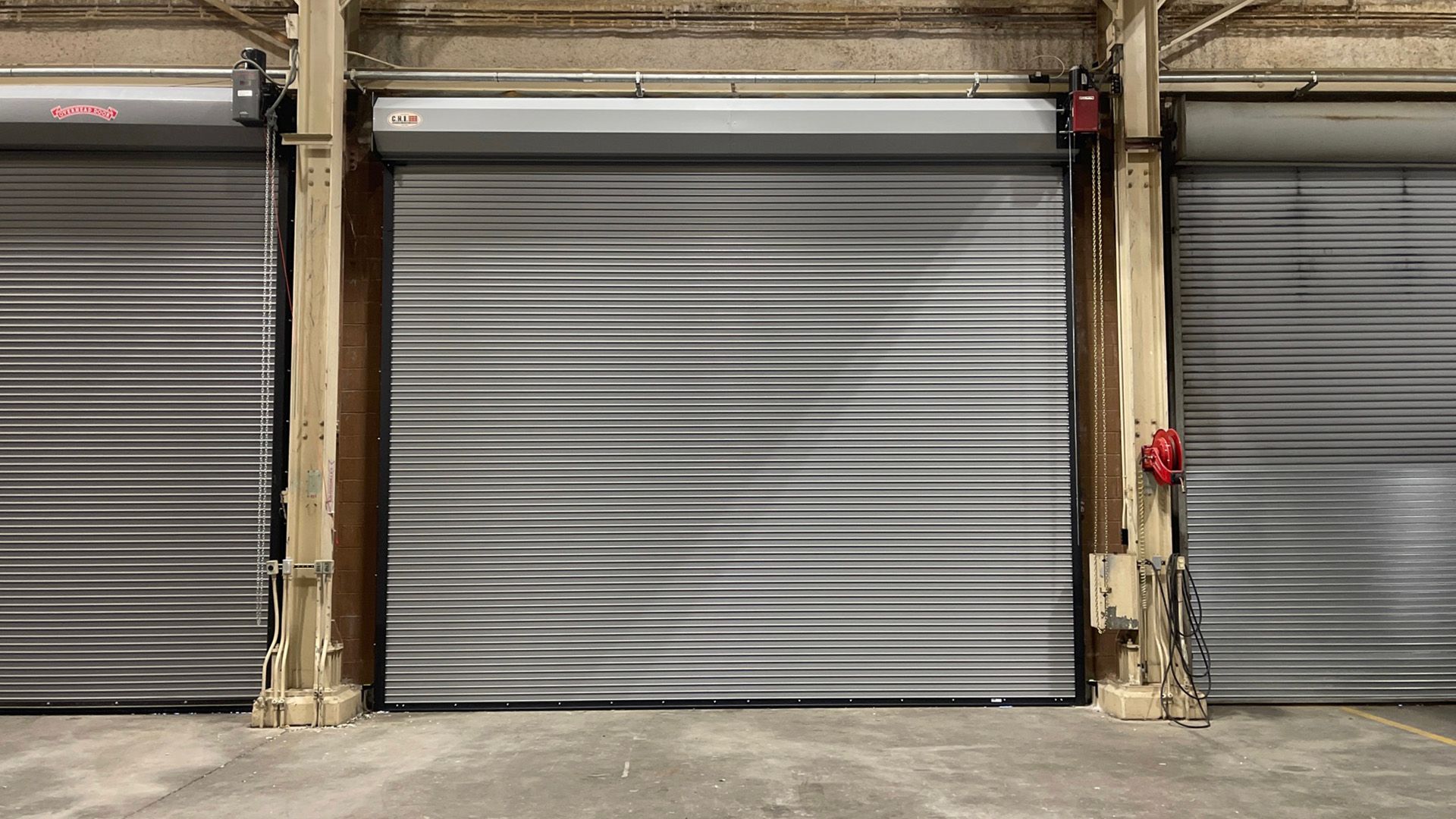 Row of closed gray metal shop shutters in an industrial building interior