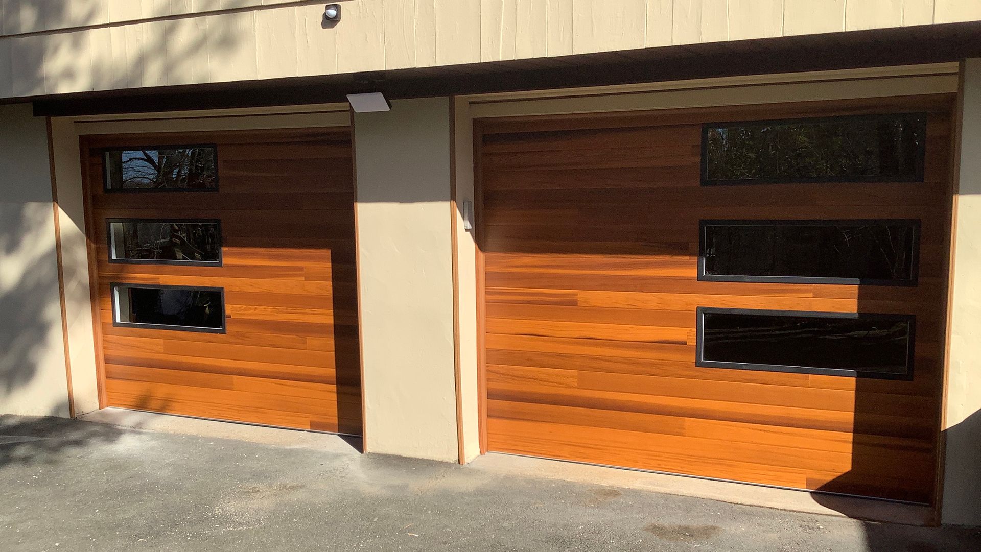 Two wooden garage doors with black framed windows.