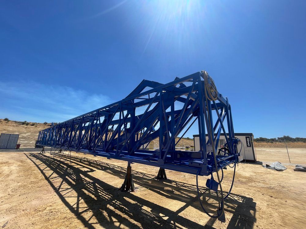 A large blue metal structure is sitting on top of a dirt field.