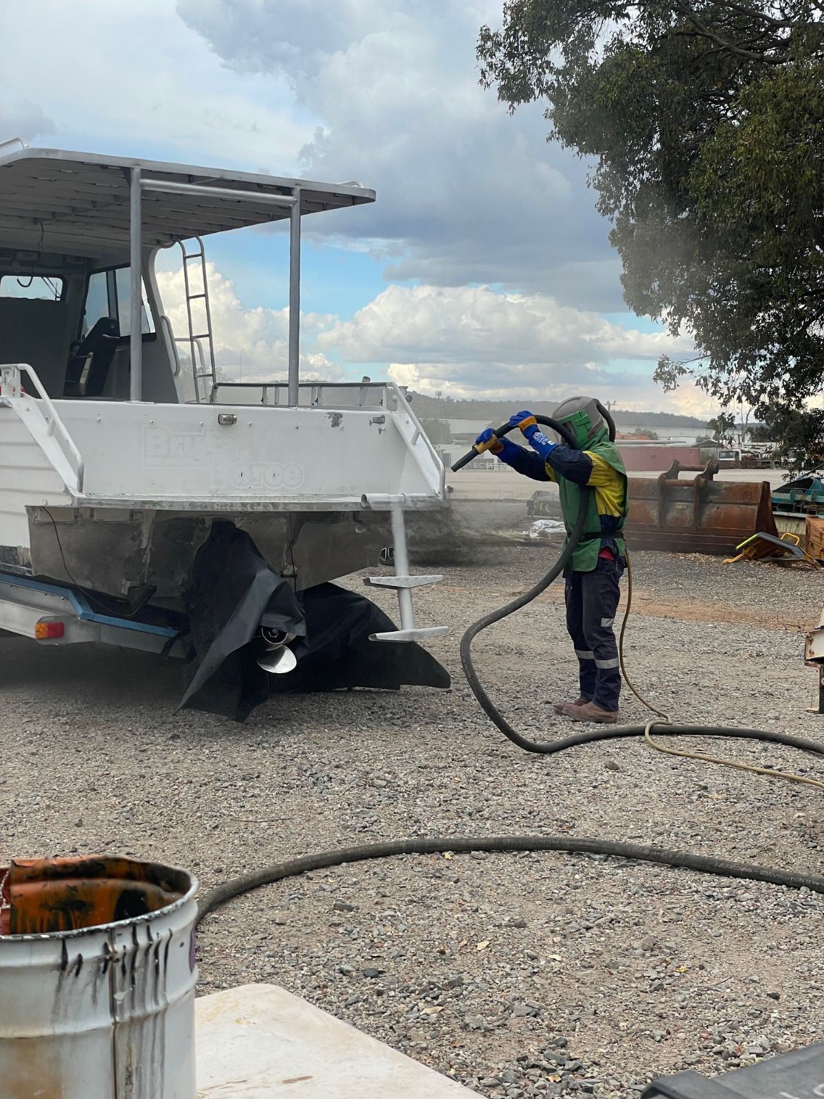 A man sandblasting a boat.