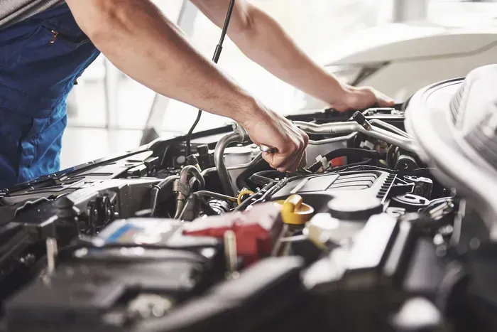 A man wearing a hard hat and gloves is working on an air conditioner.