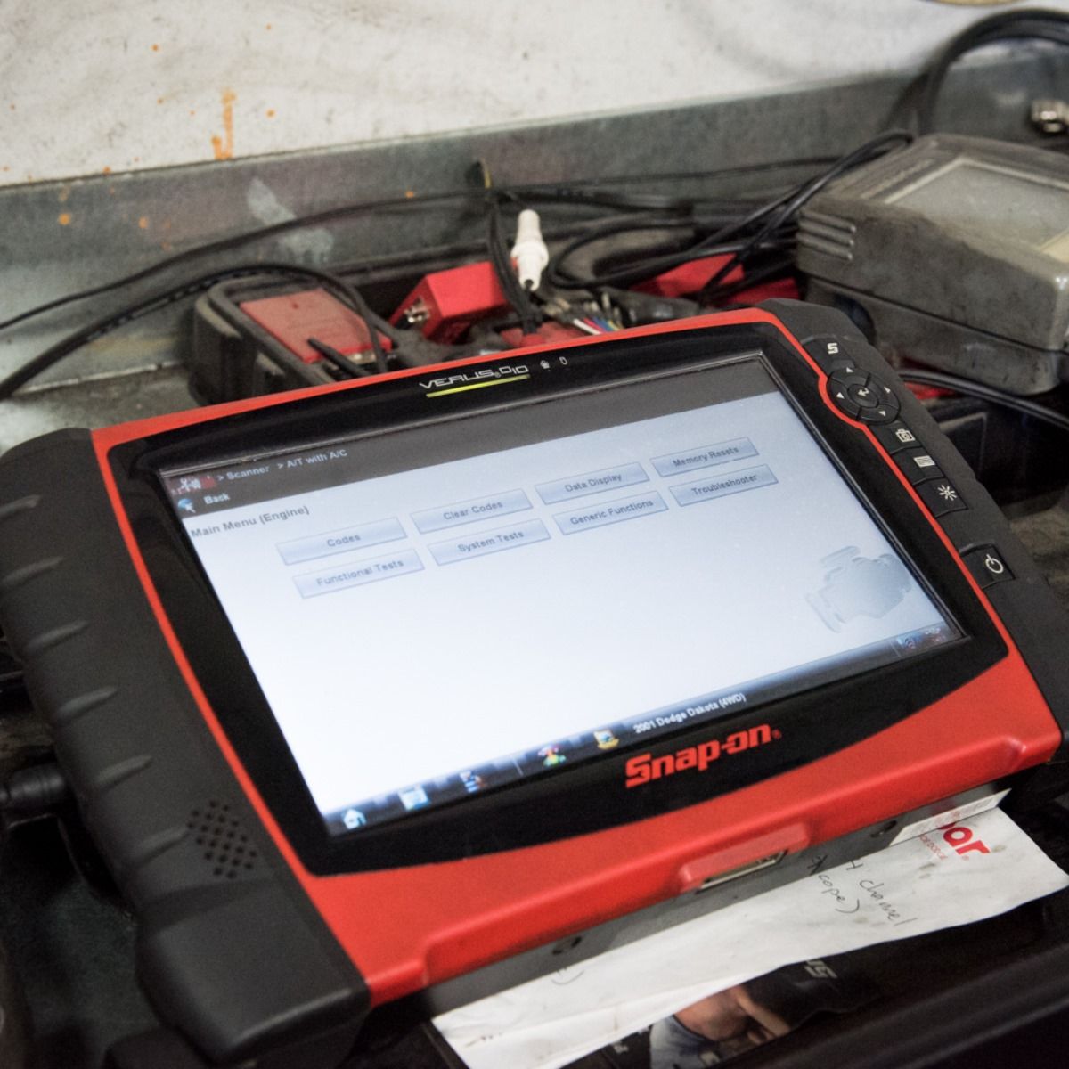 Red and black Snap-on diagnostic tablet displaying engine diagnostics in a mechanic's shop.