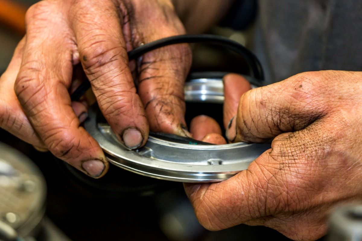 Hands with grease, inserting a rubber seal into a metal part during a repair.