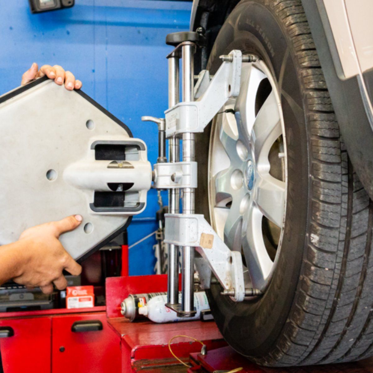 Car tire being aligned with alignment equipment in an auto repair shop.