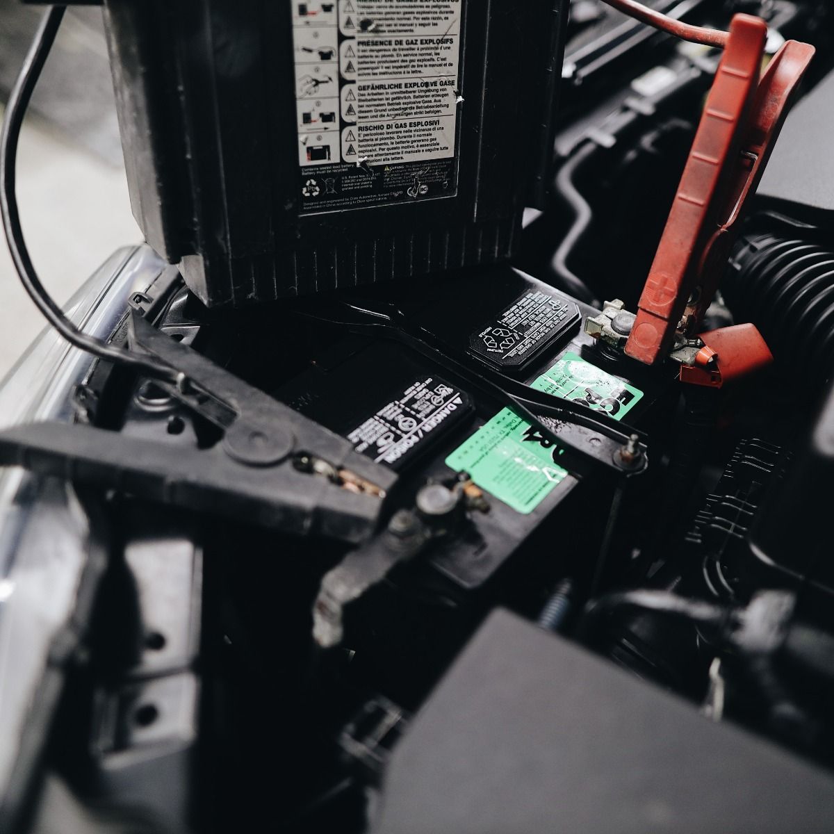 Car battery being jump started, with jumper cables connected to terminals.