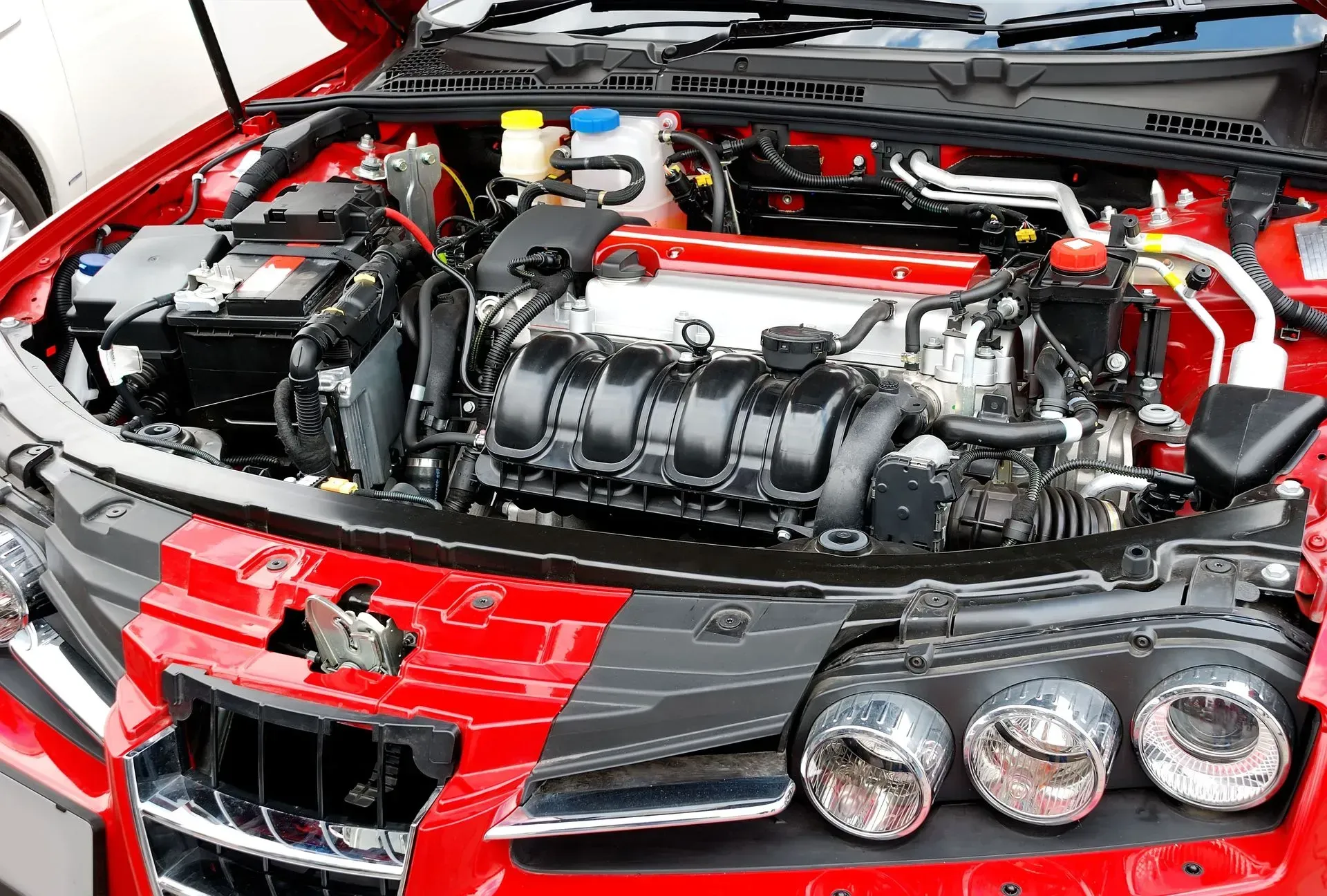 Red car engine with black and silver components; hood open.