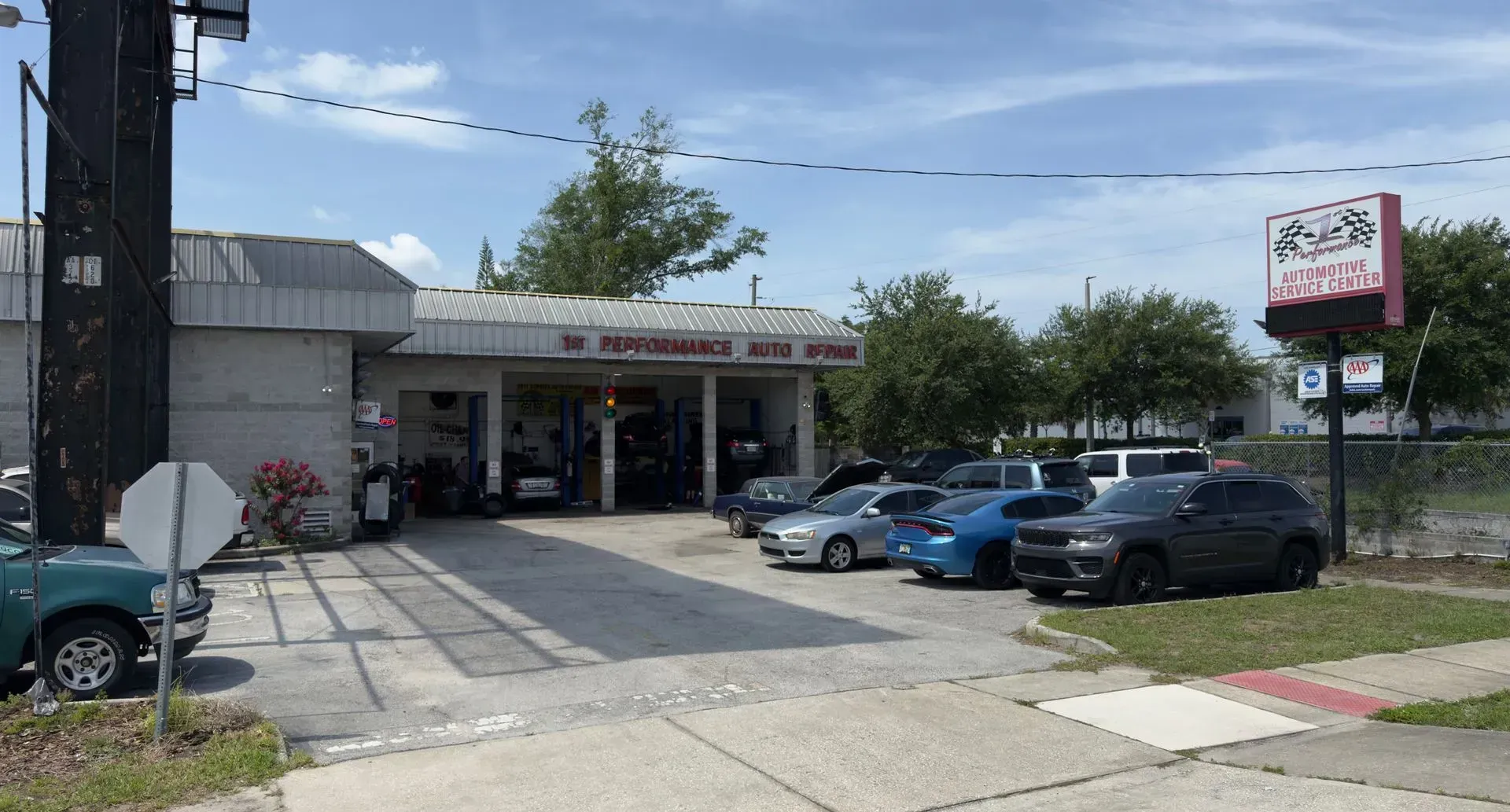 Exterior of an auto repair shop with several cars parked out front on a sunny day.