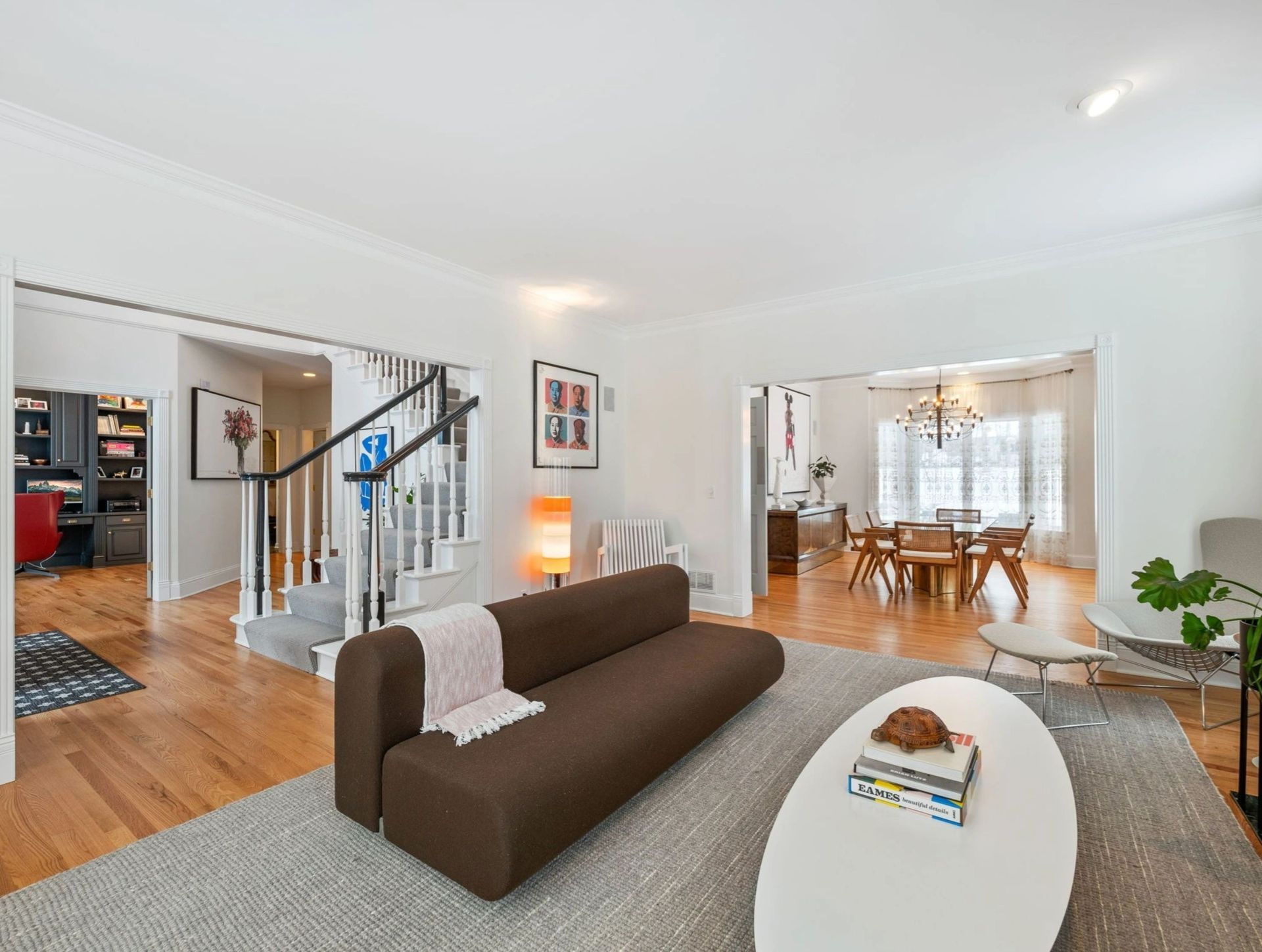 Living room with brown sofa, white oval coffee table, and open doorway to dining area.
