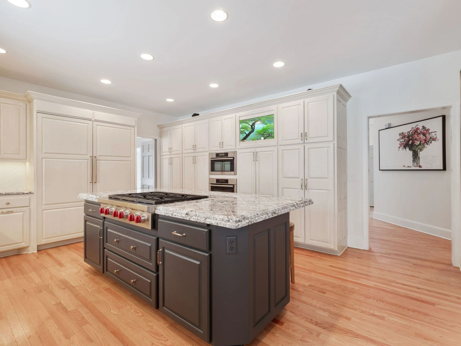 Spacious kitchen with a dark gray island, stainless steel range, and light cabinets.