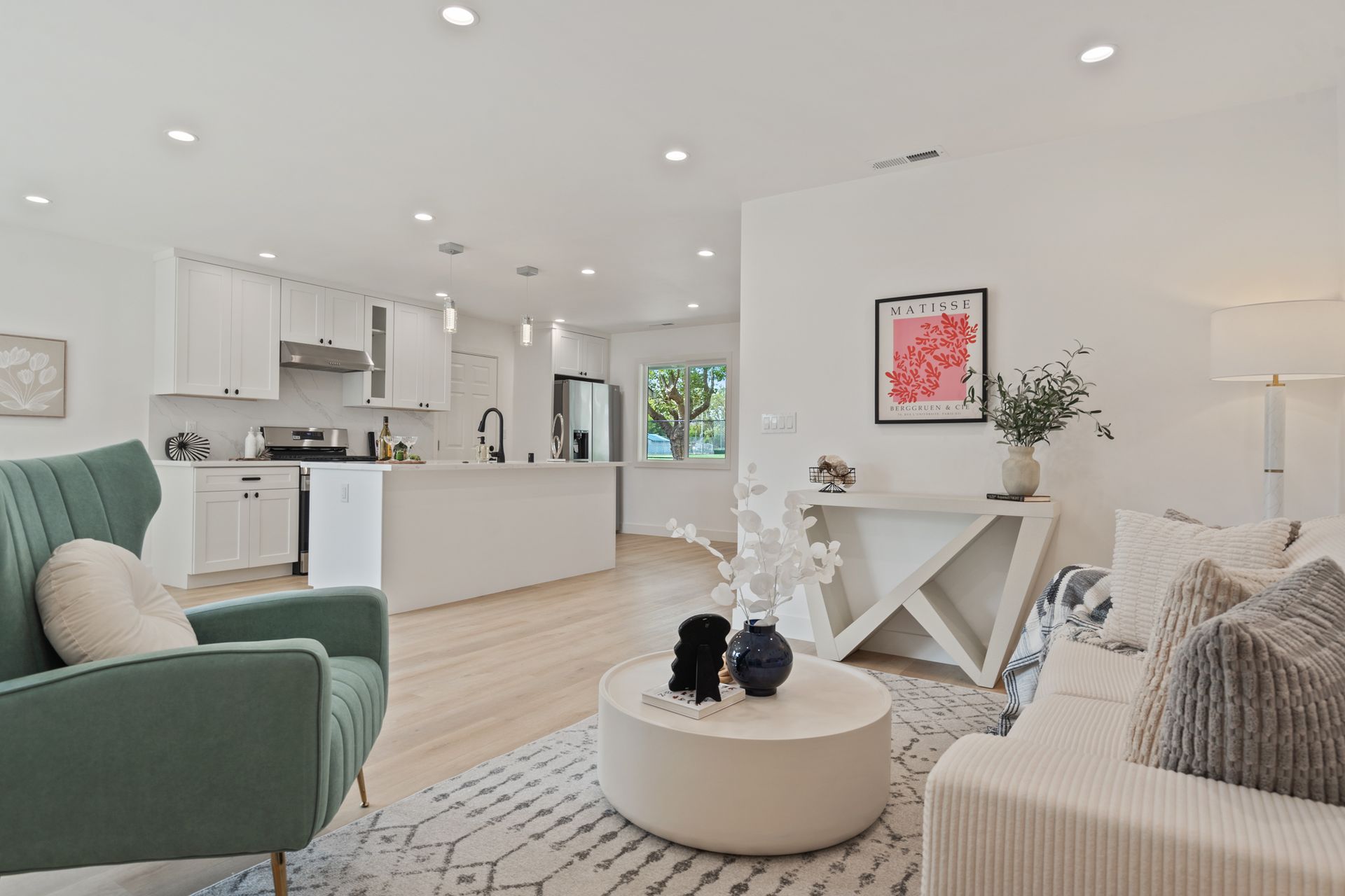 A living room with a couch , chair , coffee table and kitchen.