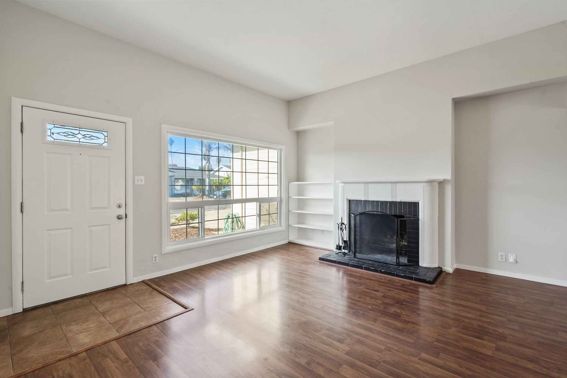 An empty living room with hardwood floors and a fireplace.