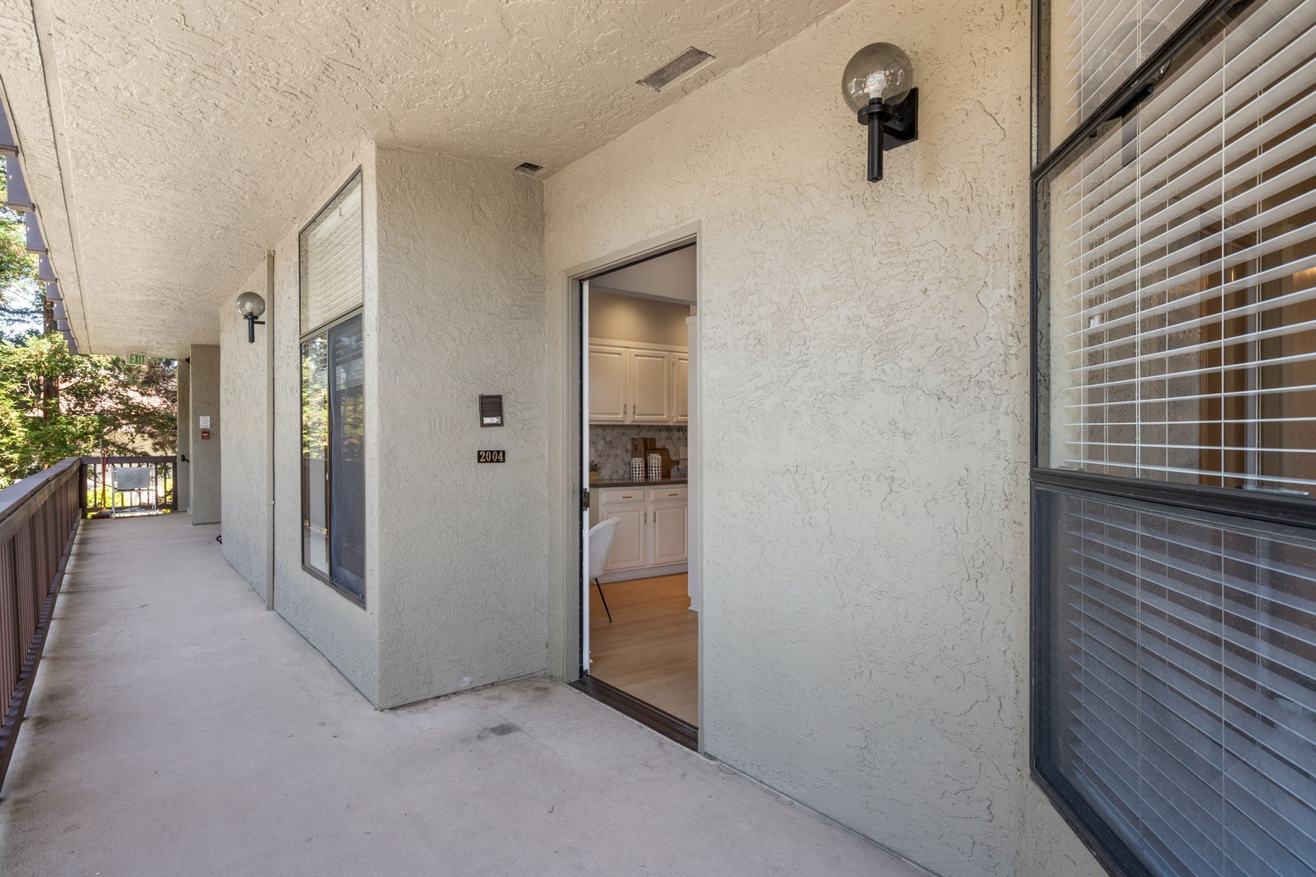 A balcony with a sliding glass door leading to a kitchen.