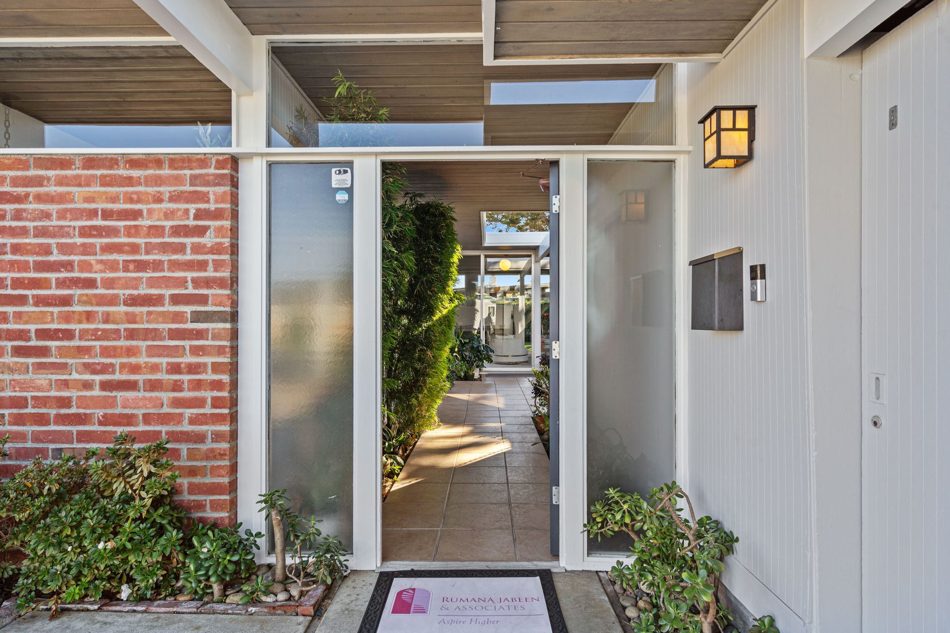The front door of a house with a brick wall and a glass door.