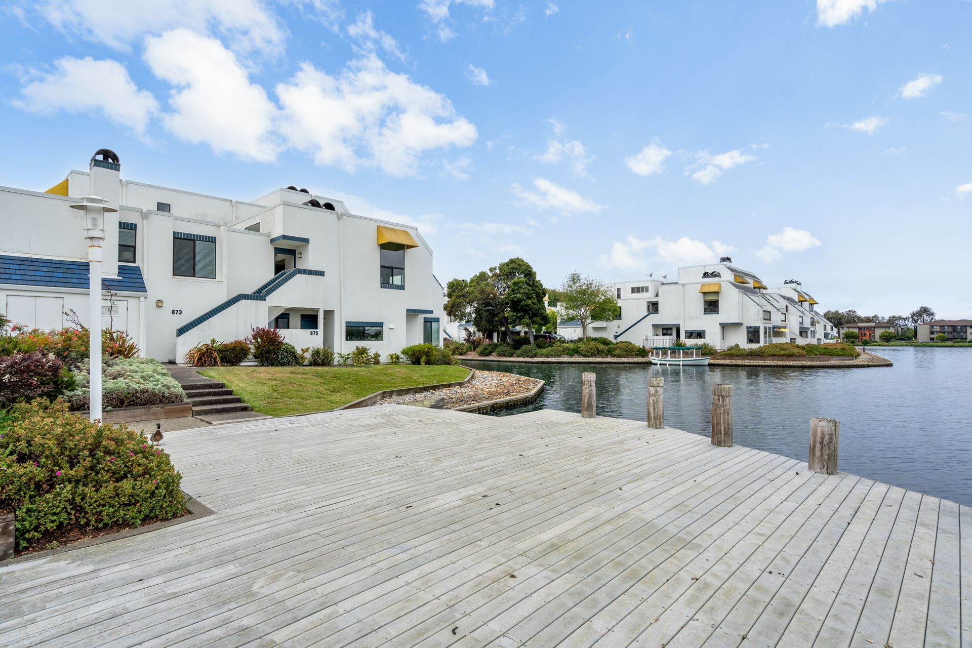 A dock in front of a white building next to a body of water.