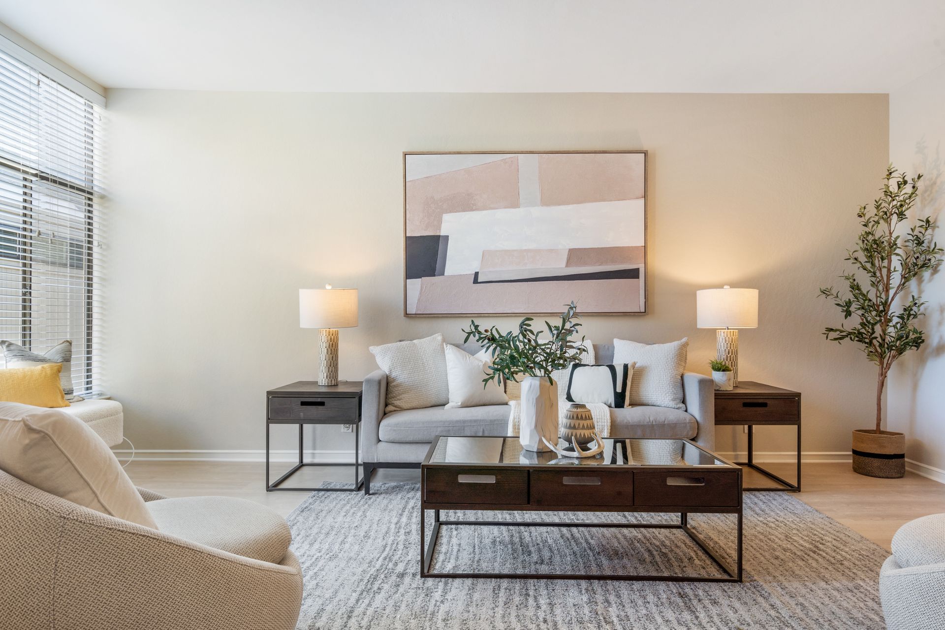 A living room with a couch , chair , coffee table and a painting on the wall.