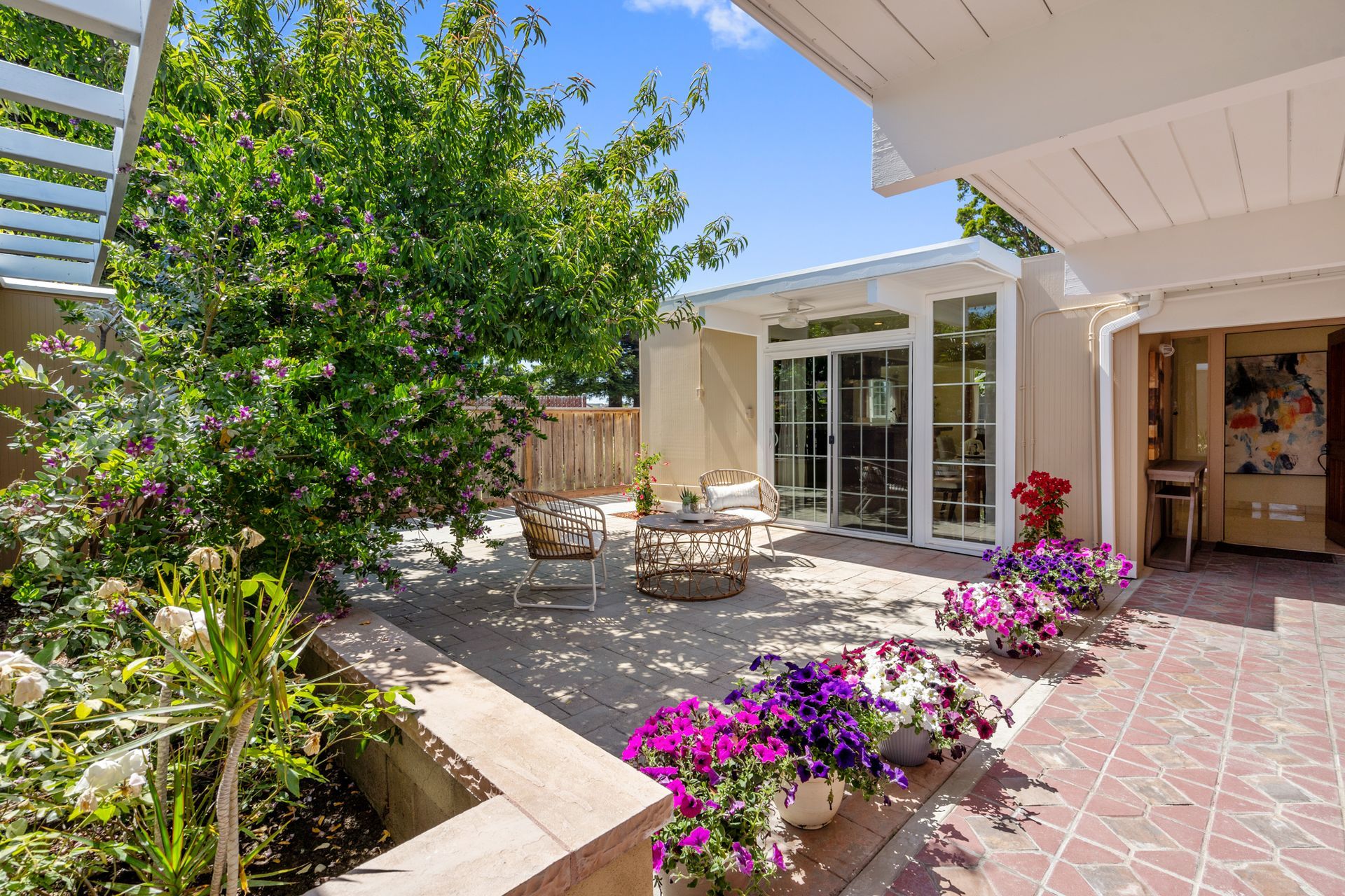 A house with a patio and flowers in front of it.