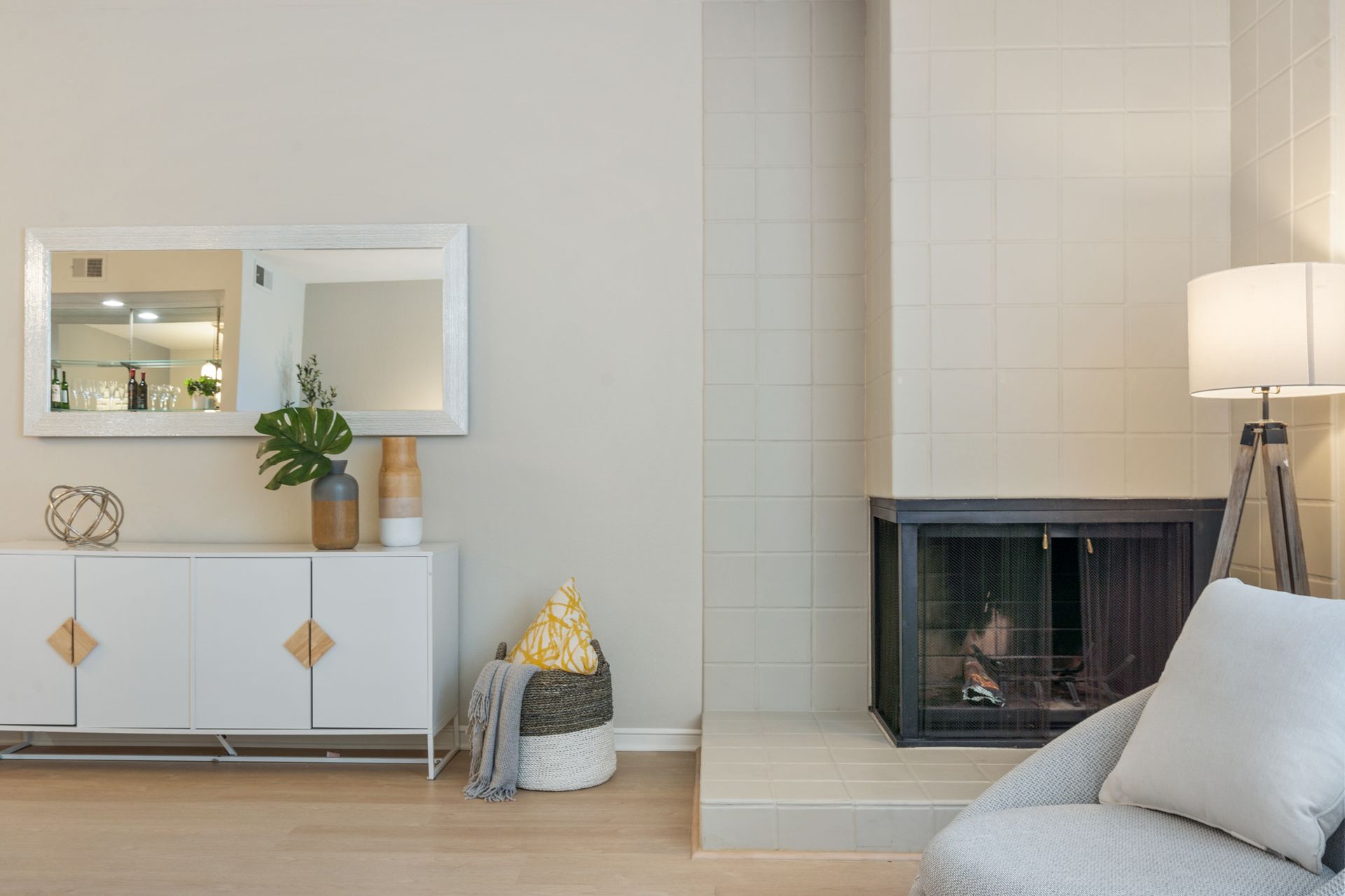 A living room with a fireplace , chair , dresser and mirror.