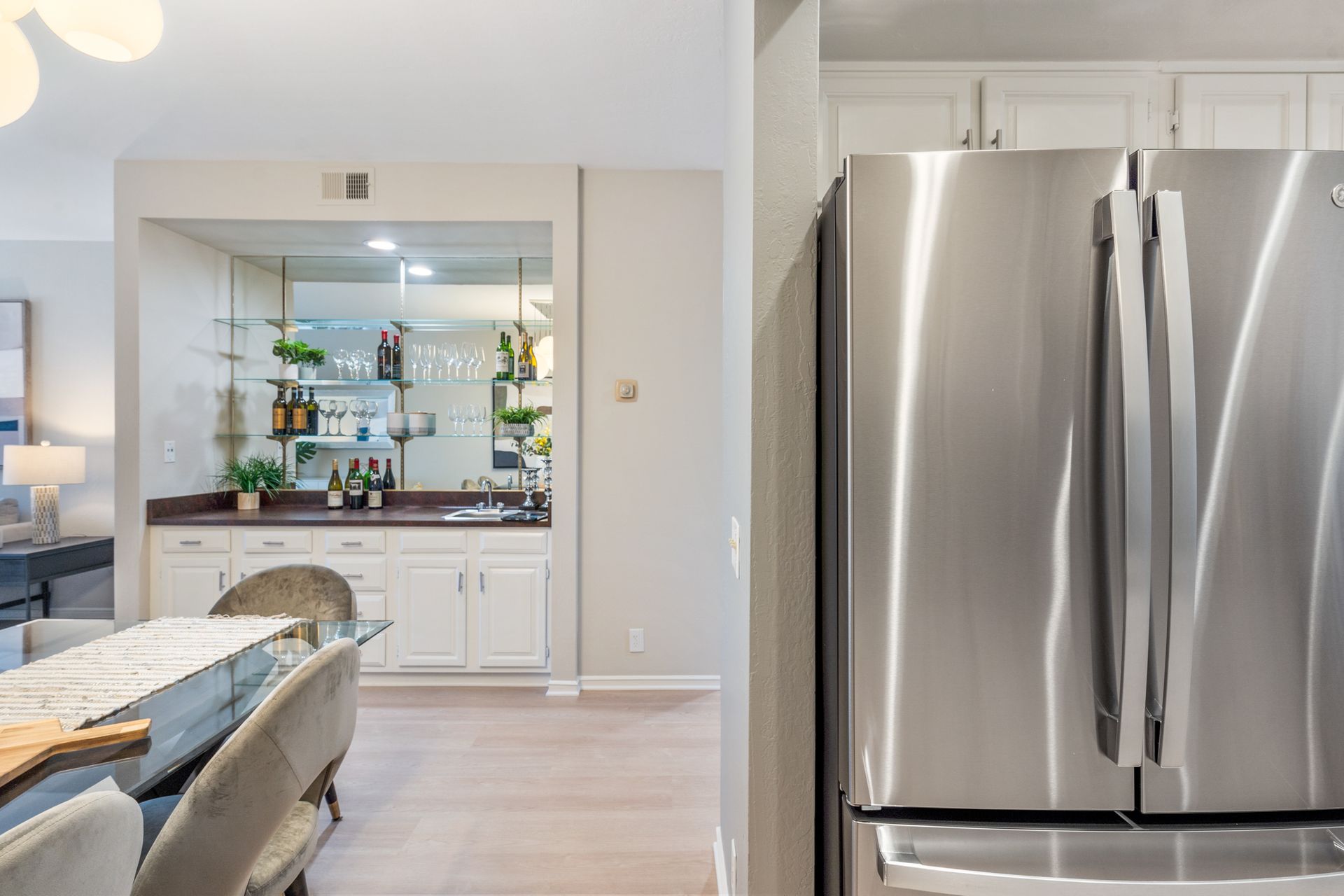 A stainless steel refrigerator is sitting in a kitchen next to a dining room.