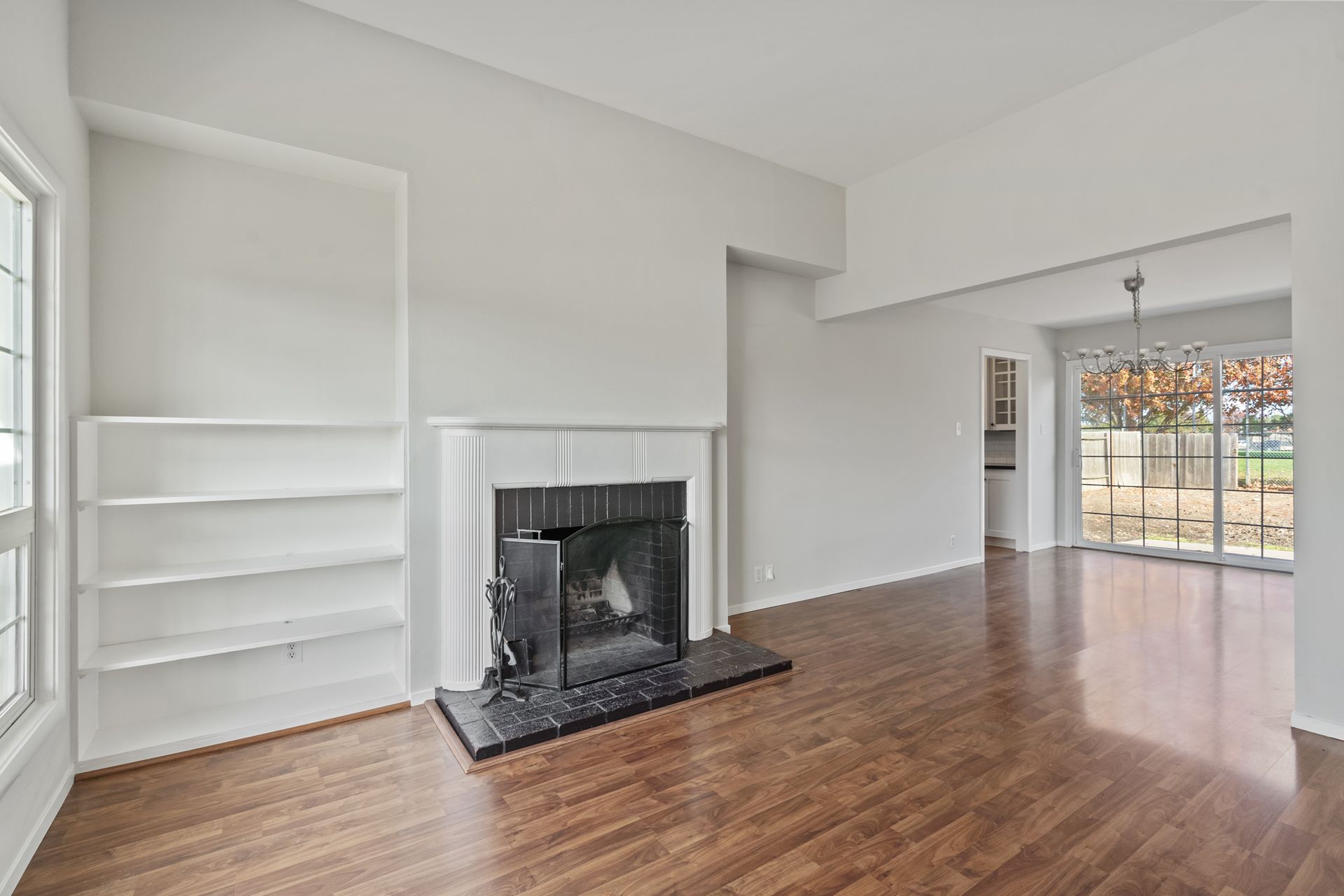 An empty living room with hardwood floors and a fireplace.