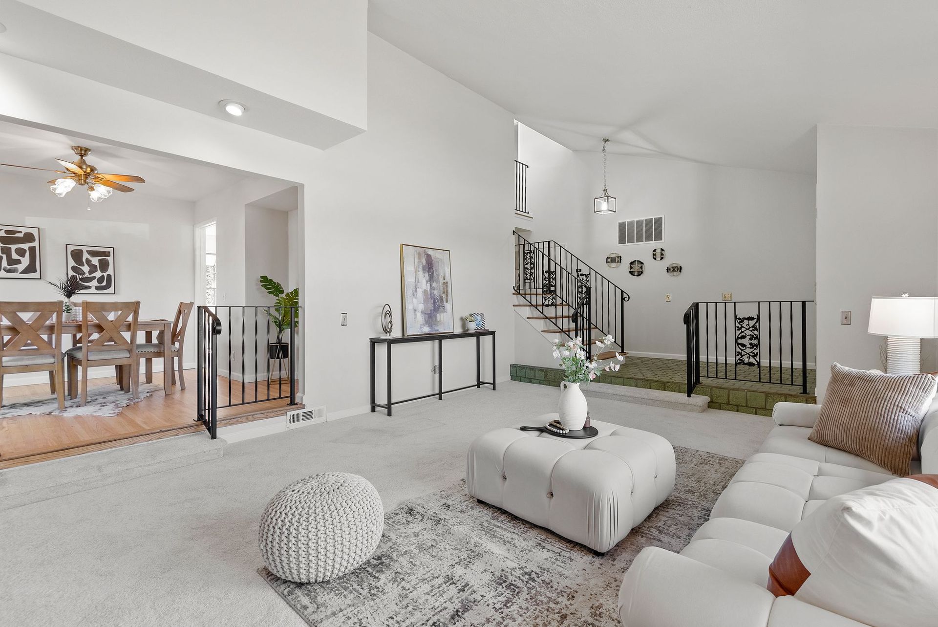 A living room with a couch , coffee table , rug and stairs.