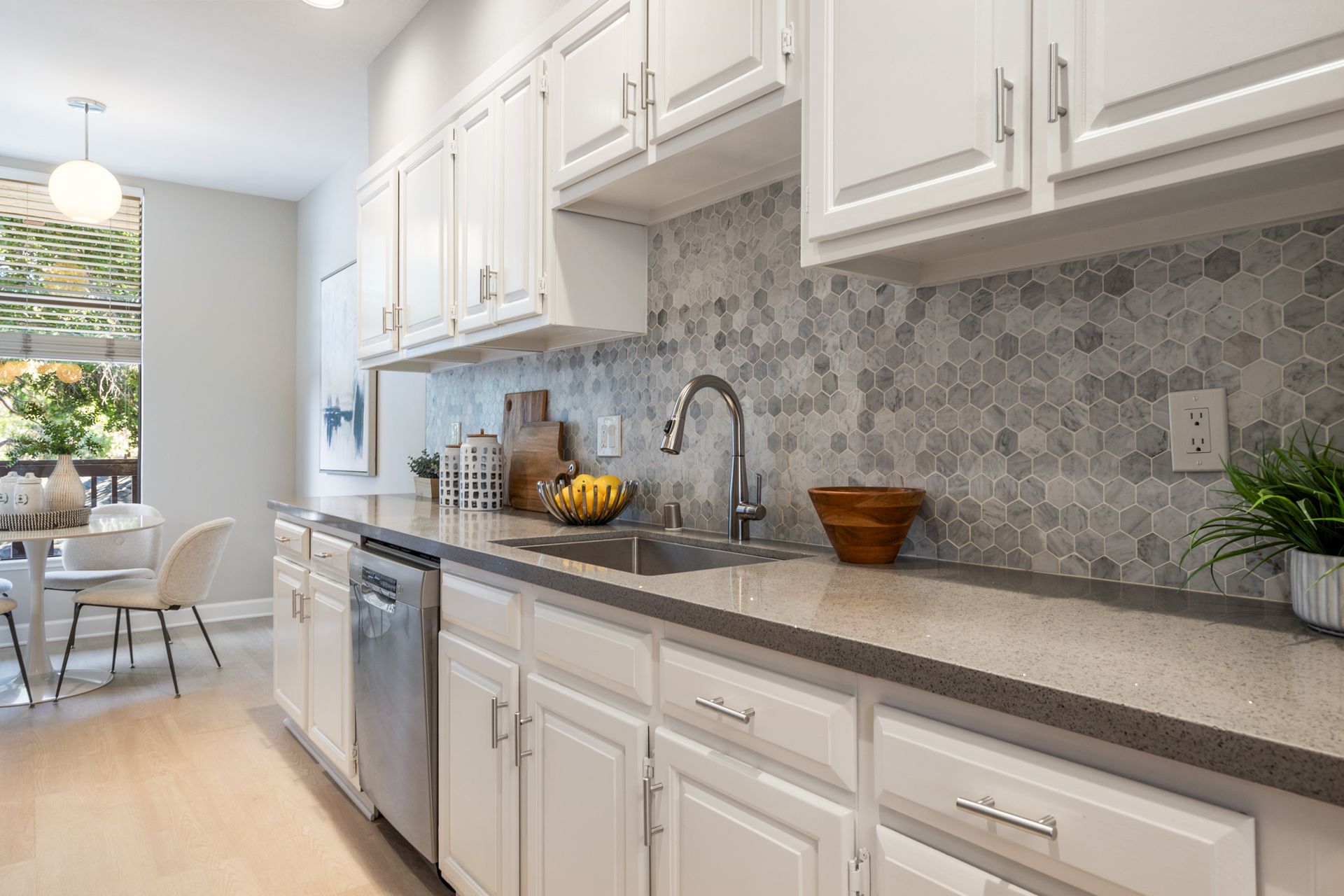 A kitchen with white cabinets , a sink , and a dishwasher.