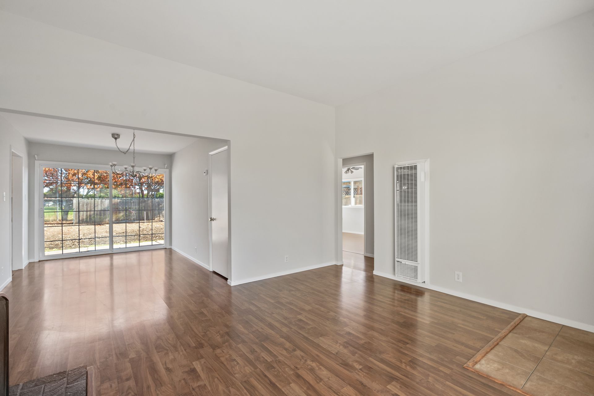An empty living room with hardwood floors and white walls.