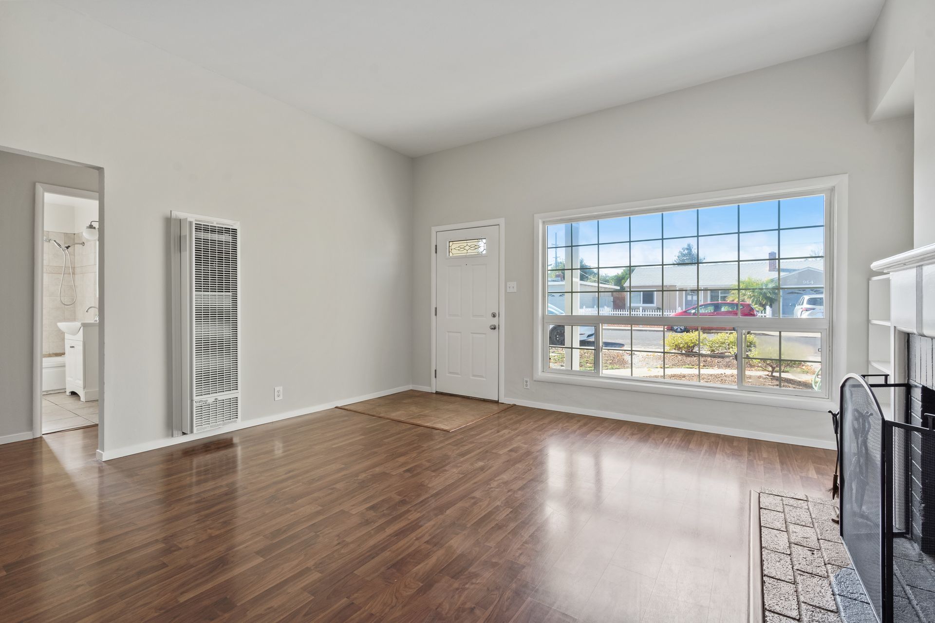 An empty living room with hardwood floors and a fireplace.