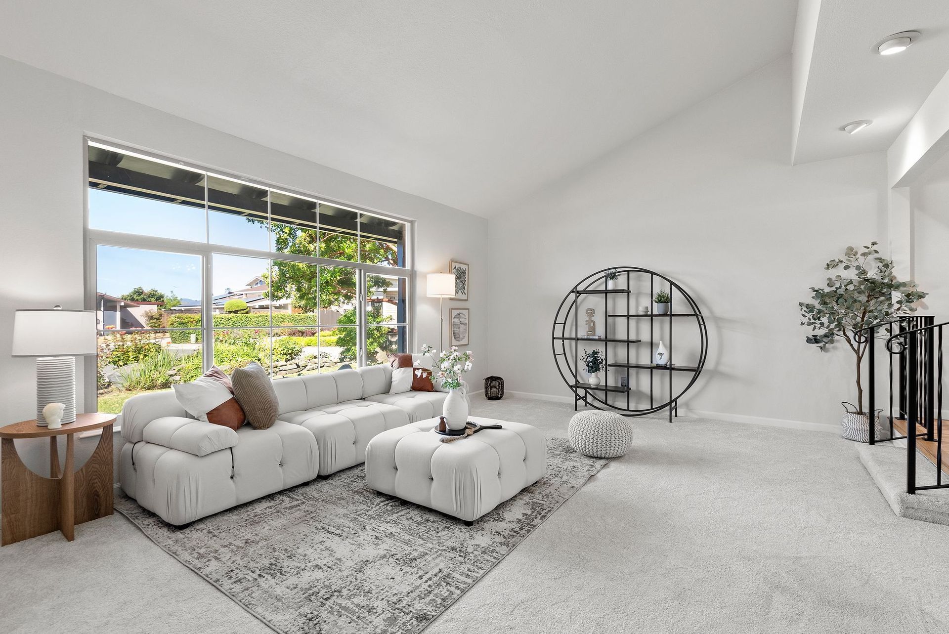 A living room with white furniture and a large window.