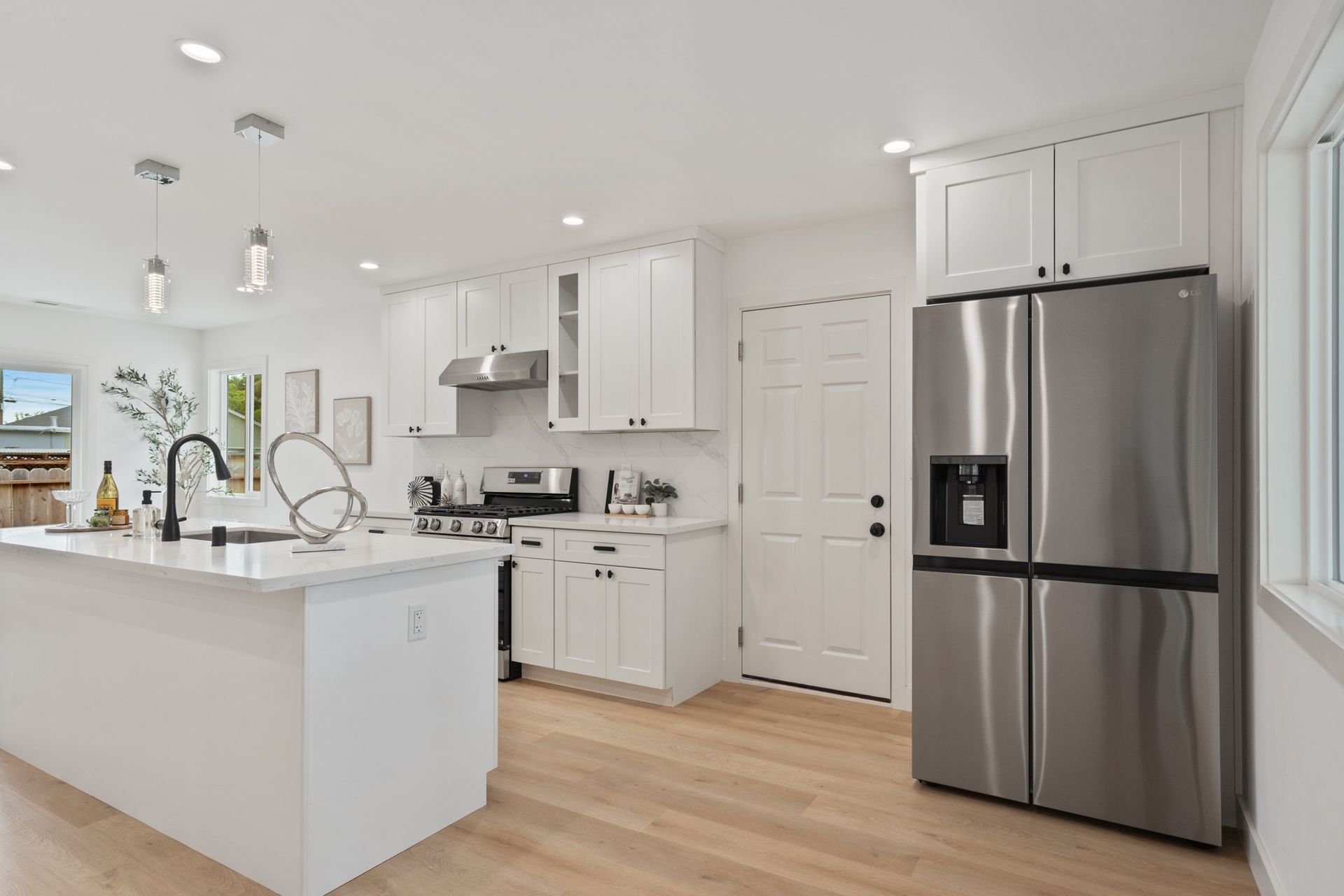 A kitchen with white cabinets and a stainless steel refrigerator.