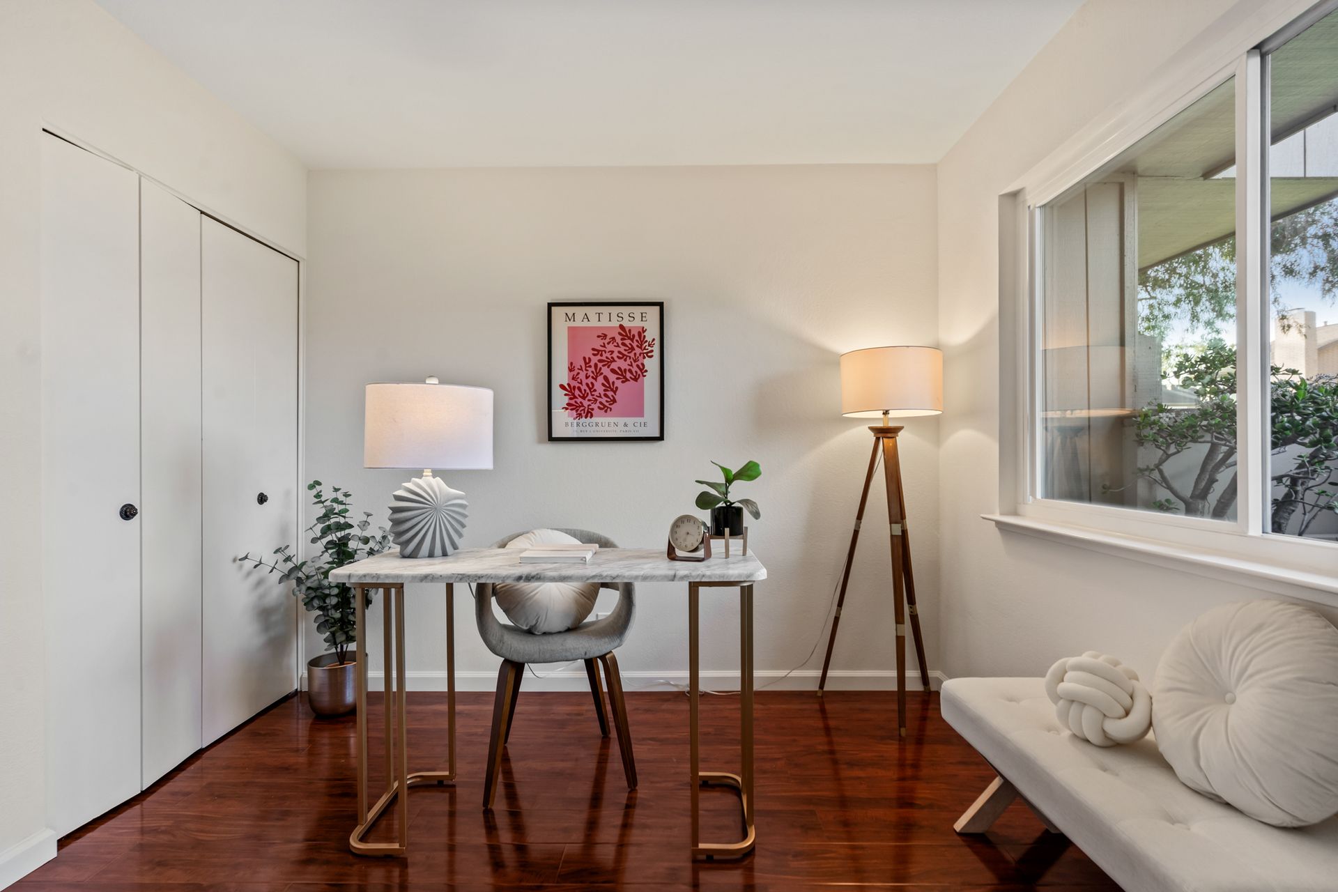 A home office with a desk , chair , lamp and window.