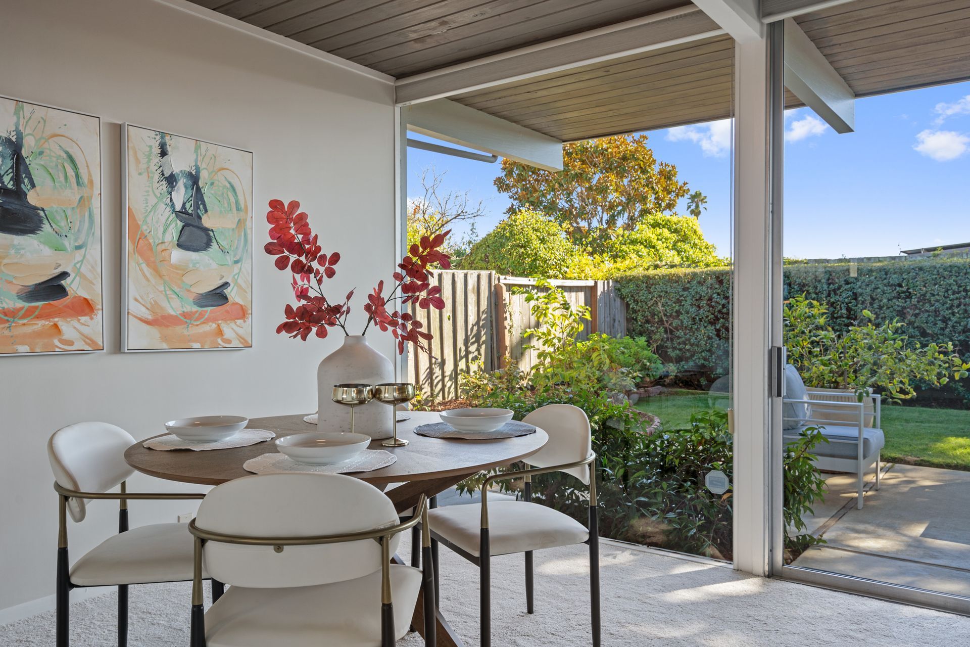 A dining room with a table and chairs and paintings on the wall