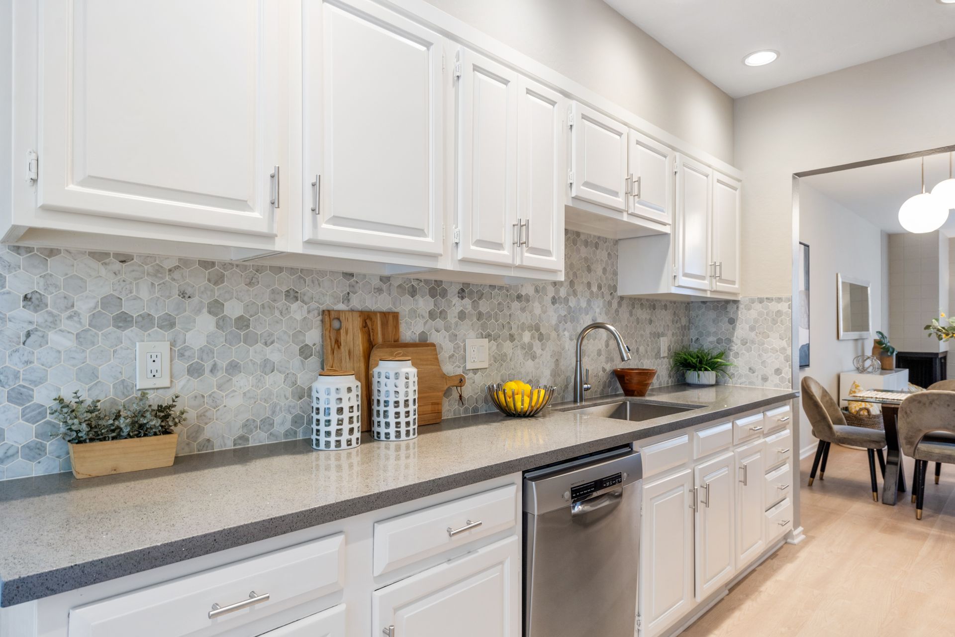 A kitchen with white cabinets and a stainless steel dishwasher.