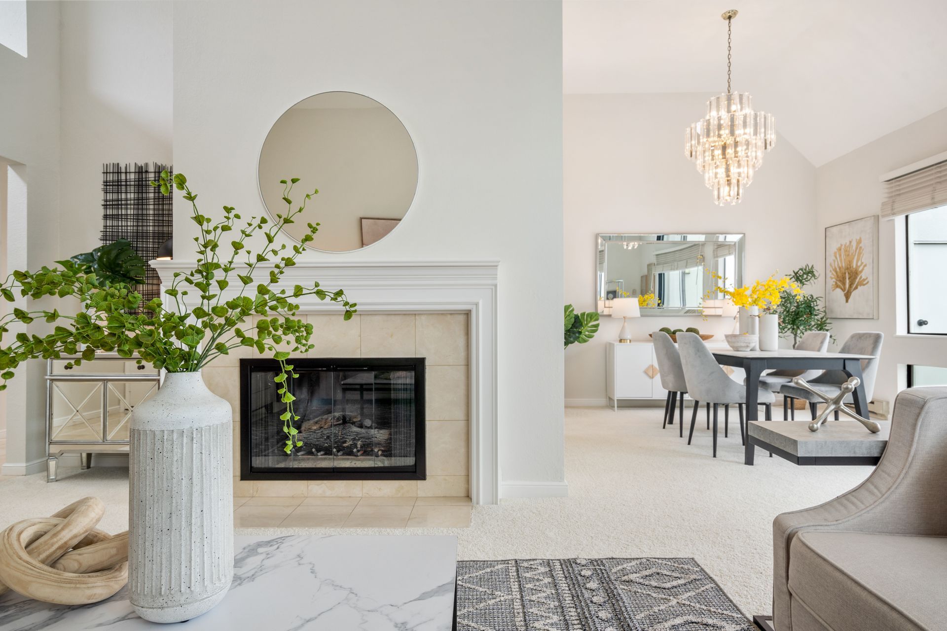 A living room with a fireplace and a dining room in the background.