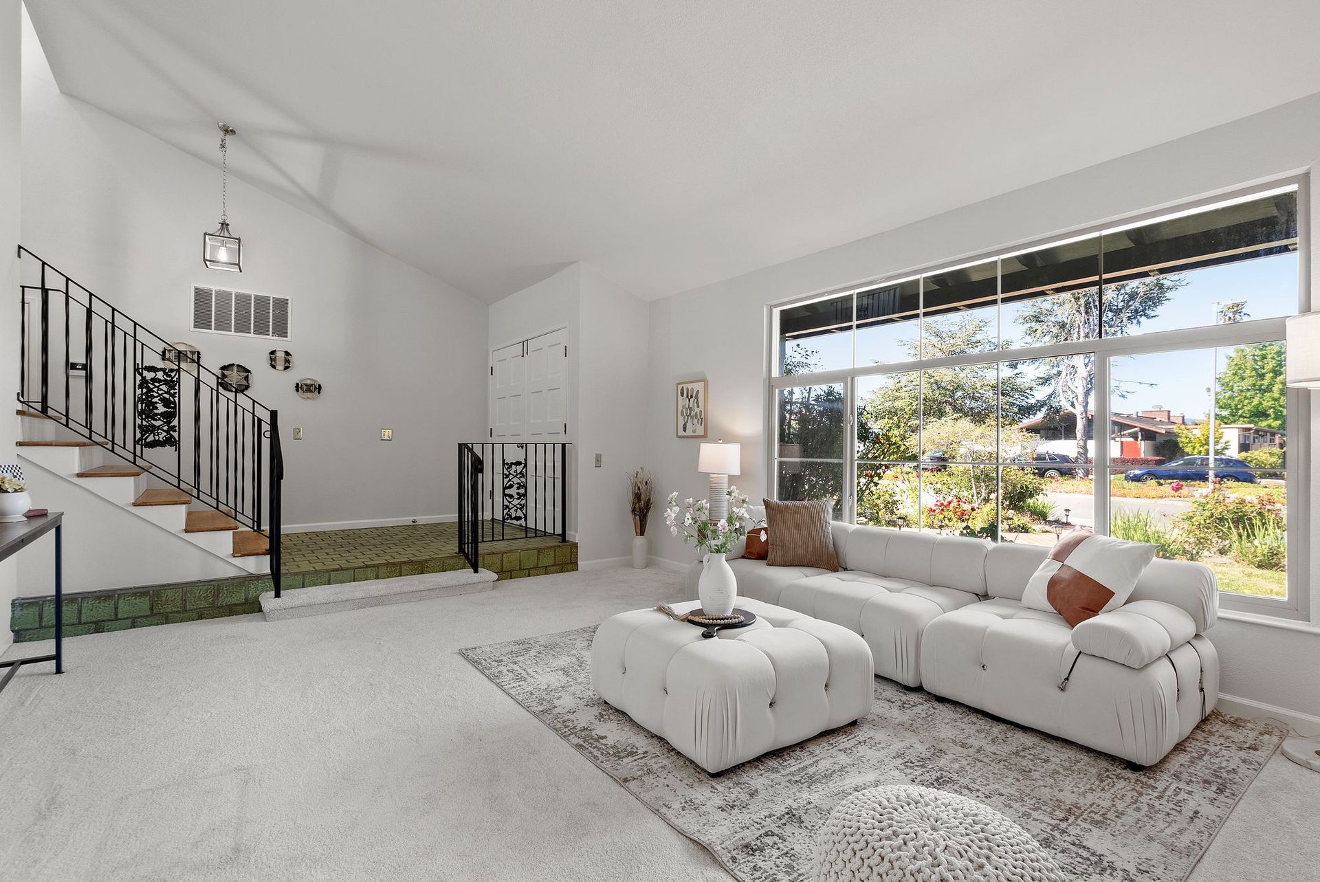 A living room with a couch , ottoman , and stairs.
