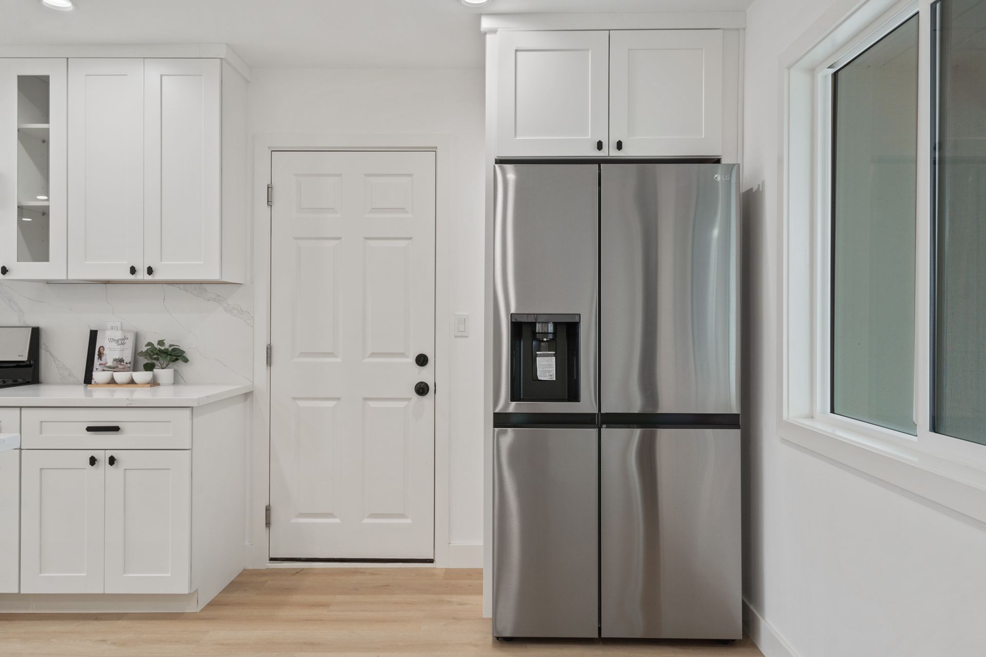 A kitchen with white cabinets and a stainless steel refrigerator.