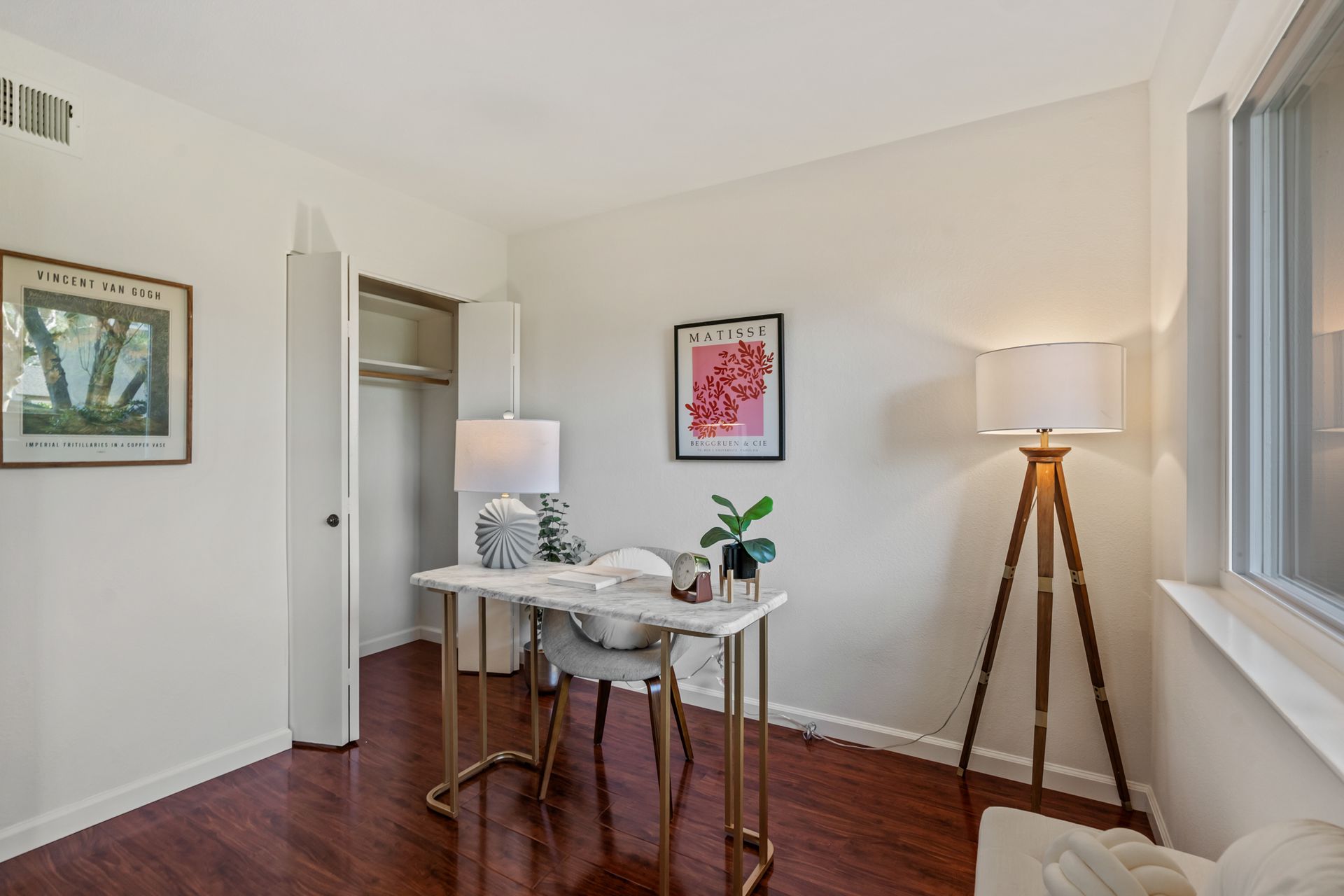 A room with a desk , chair , lamp and a window.