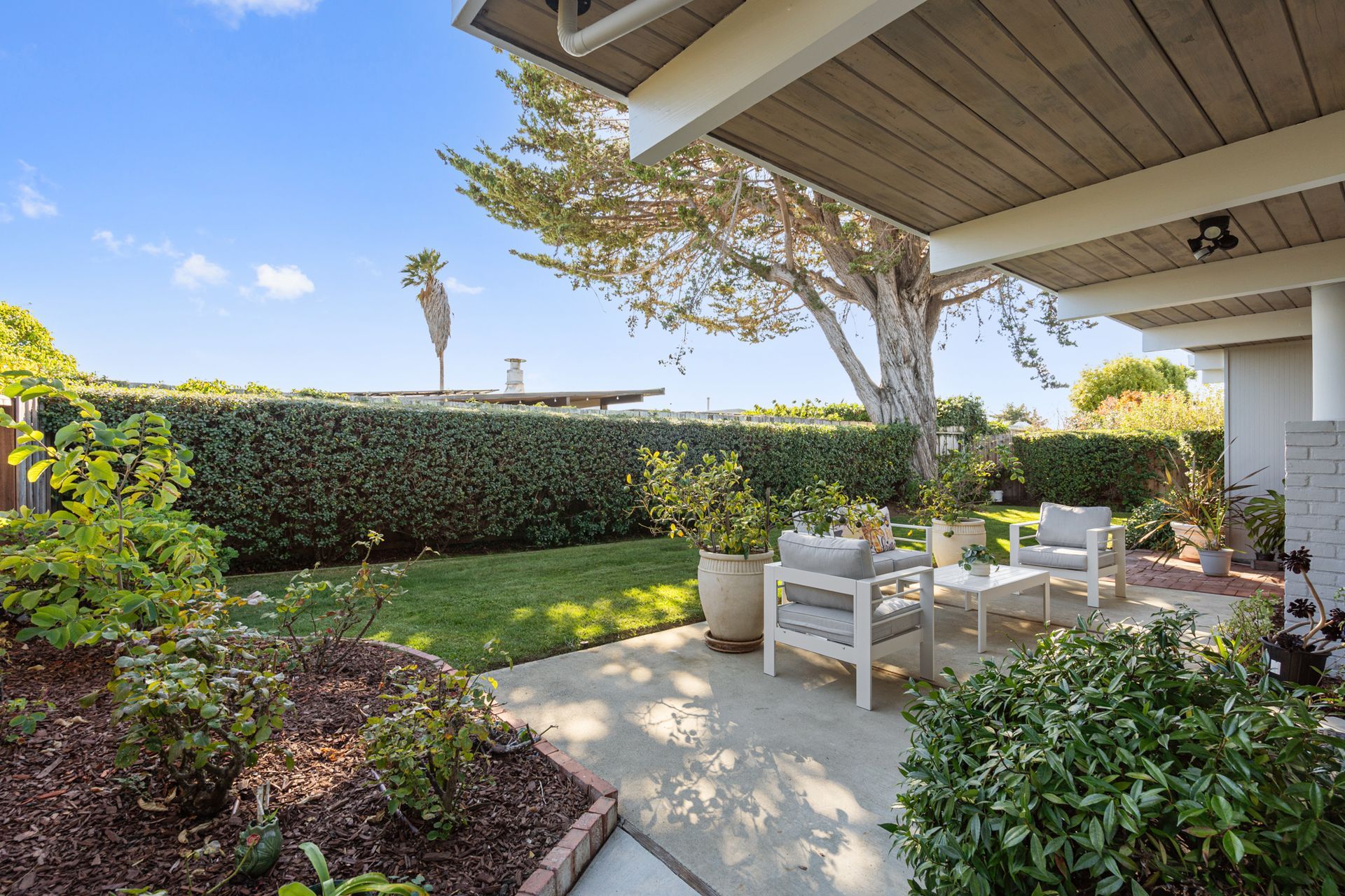 There is a patio with chairs and a table in the backyard of a house.