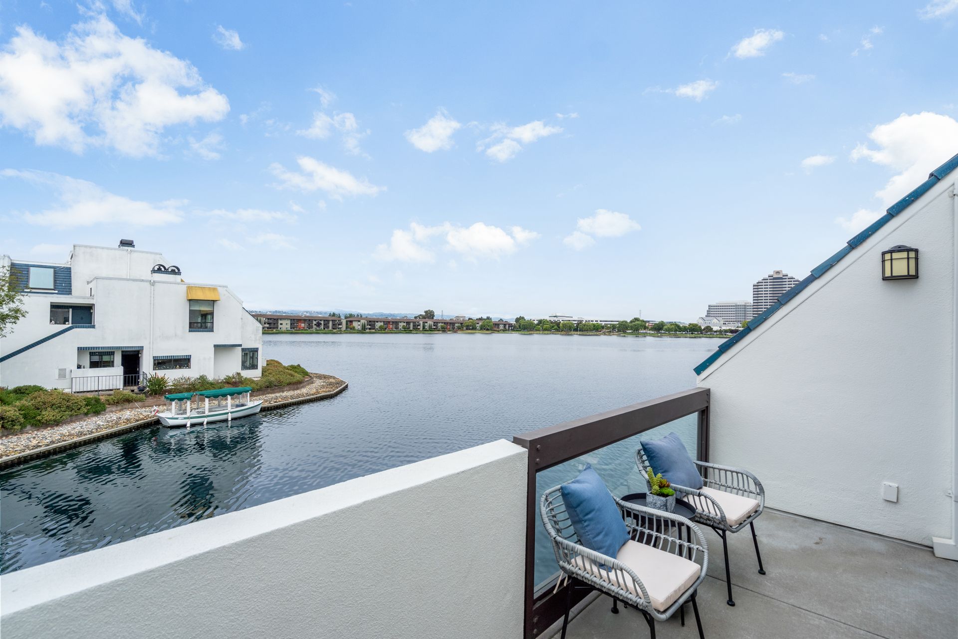 A balcony with two chairs and a table overlooking a body of water.