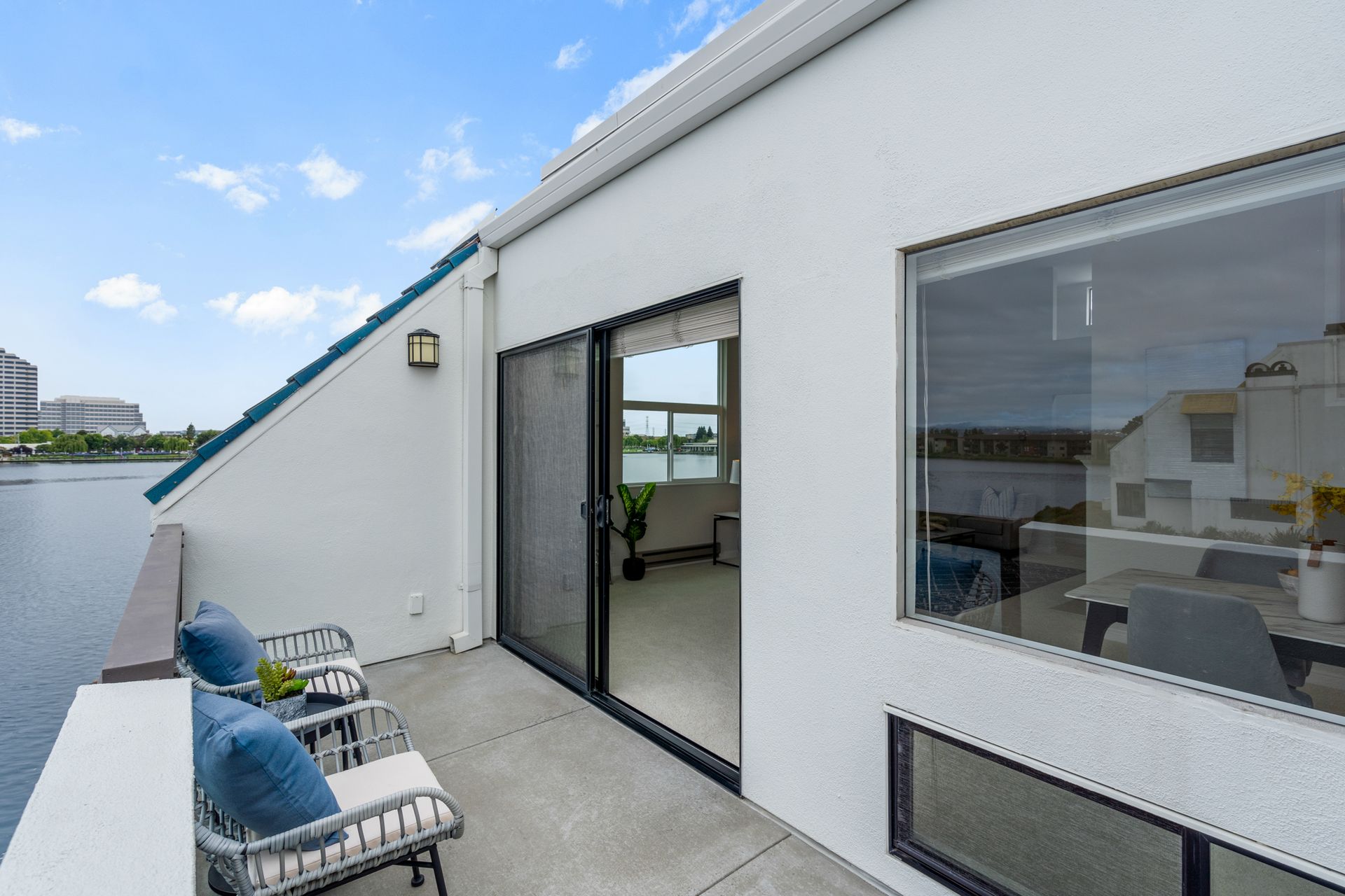 A balcony with a sliding glass door and chairs overlooking a body of water.