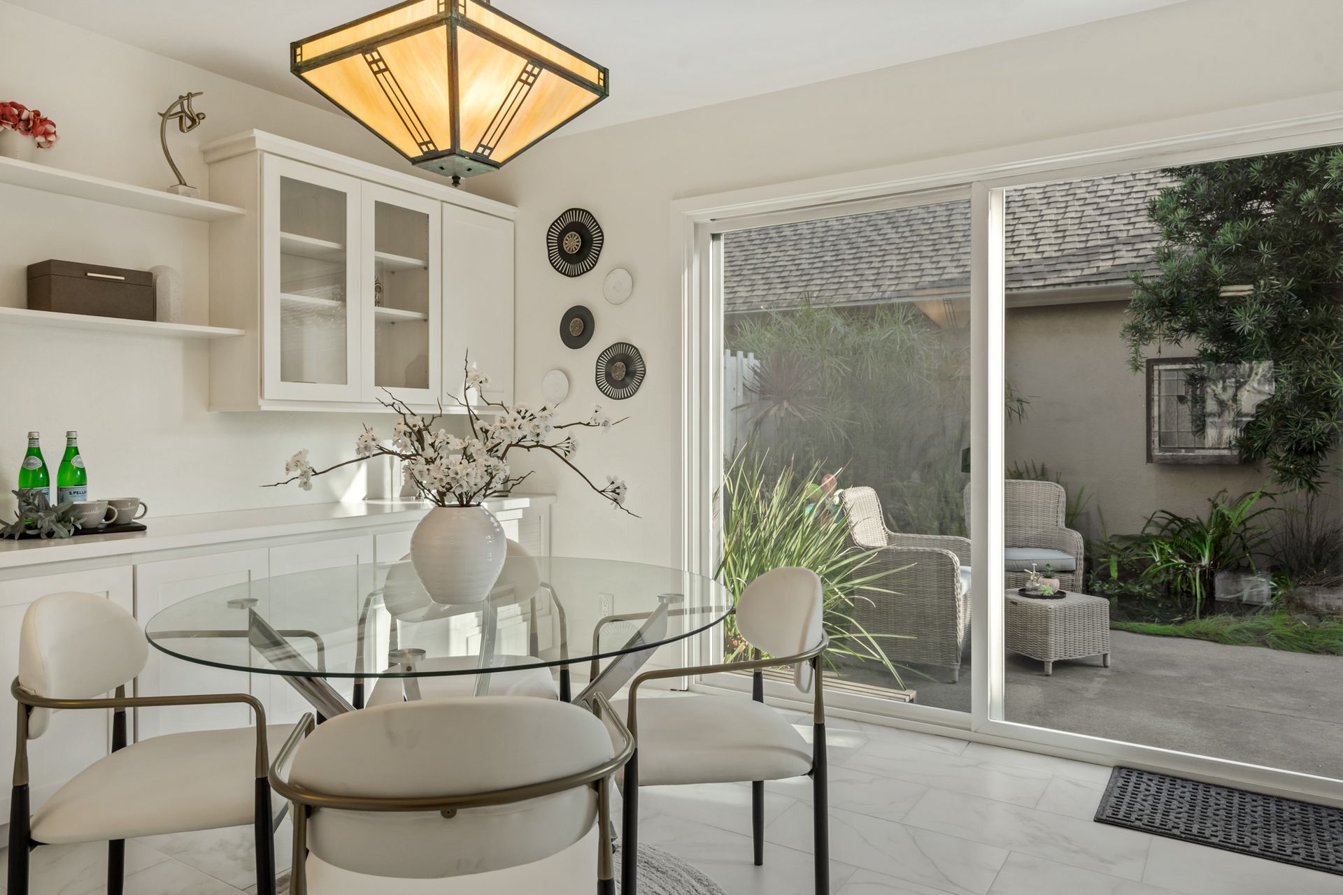 A dining room with a glass table and chairs and a sliding glass door