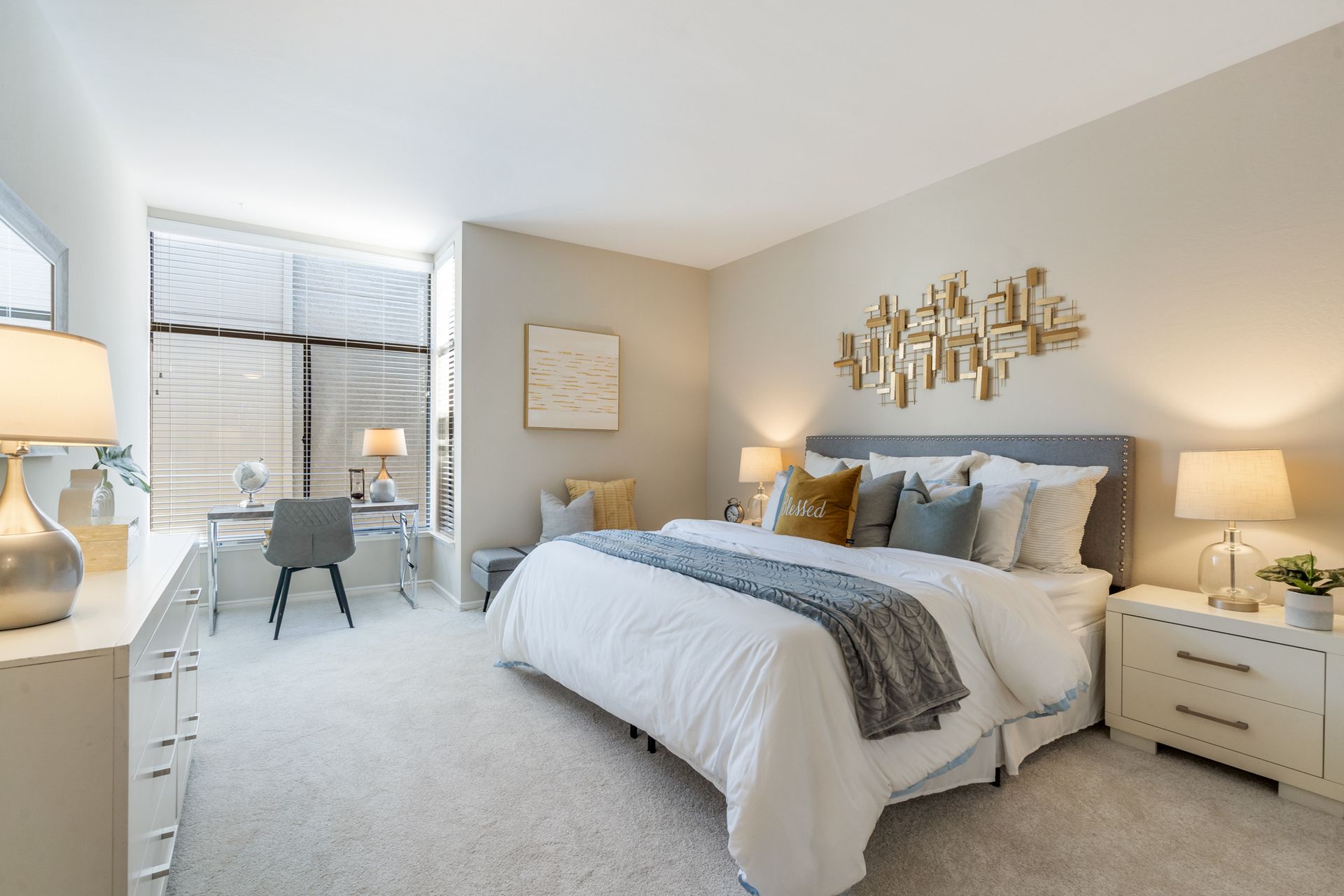 A bedroom with a large bed , dresser , nightstand and desk.