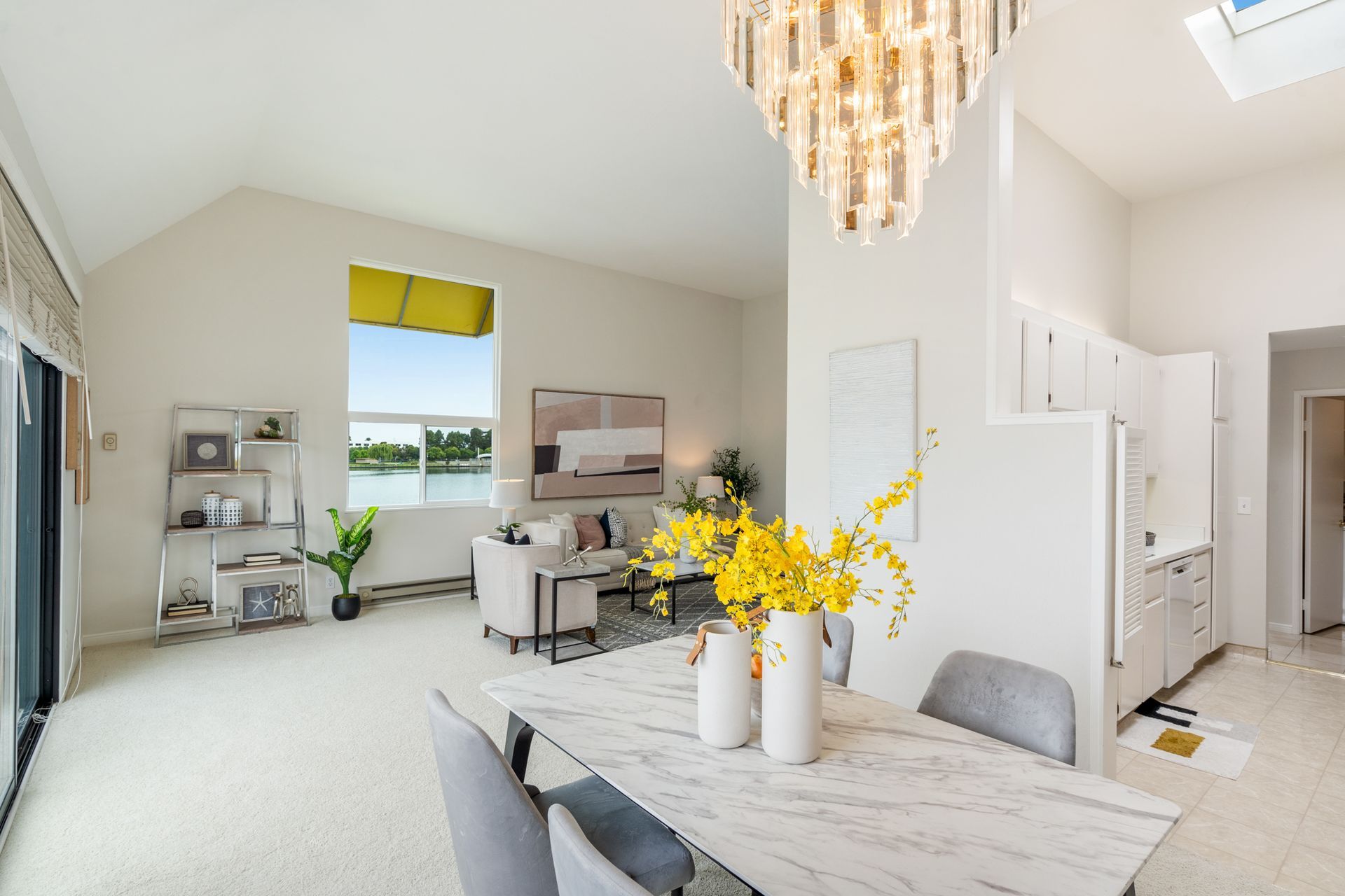 A living room with a dining table and chairs and a chandelier.
