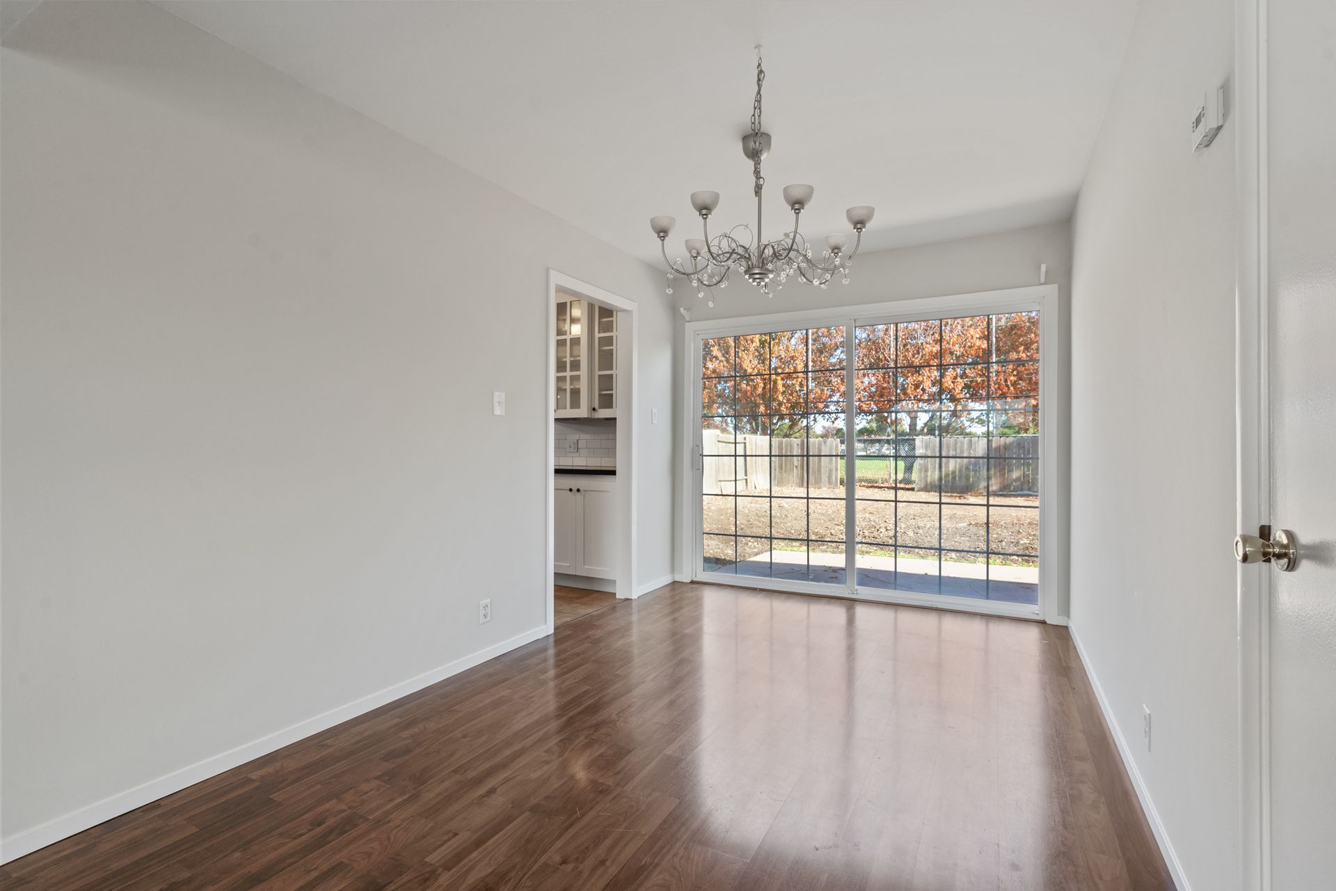 An empty living room with hardwood floors and a sliding glass door.