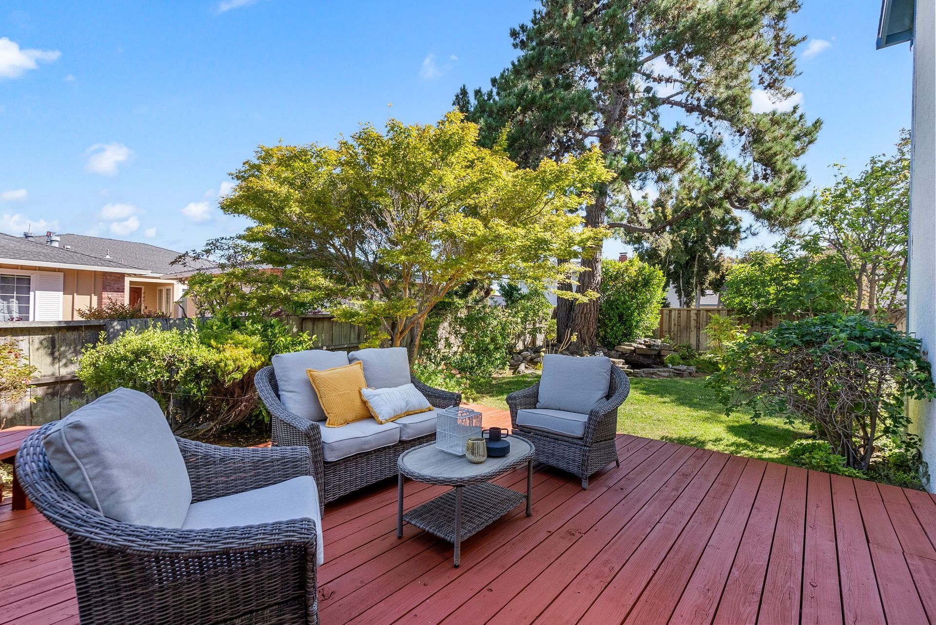 A wooden deck with wicker furniture and a couch and chairs on it.