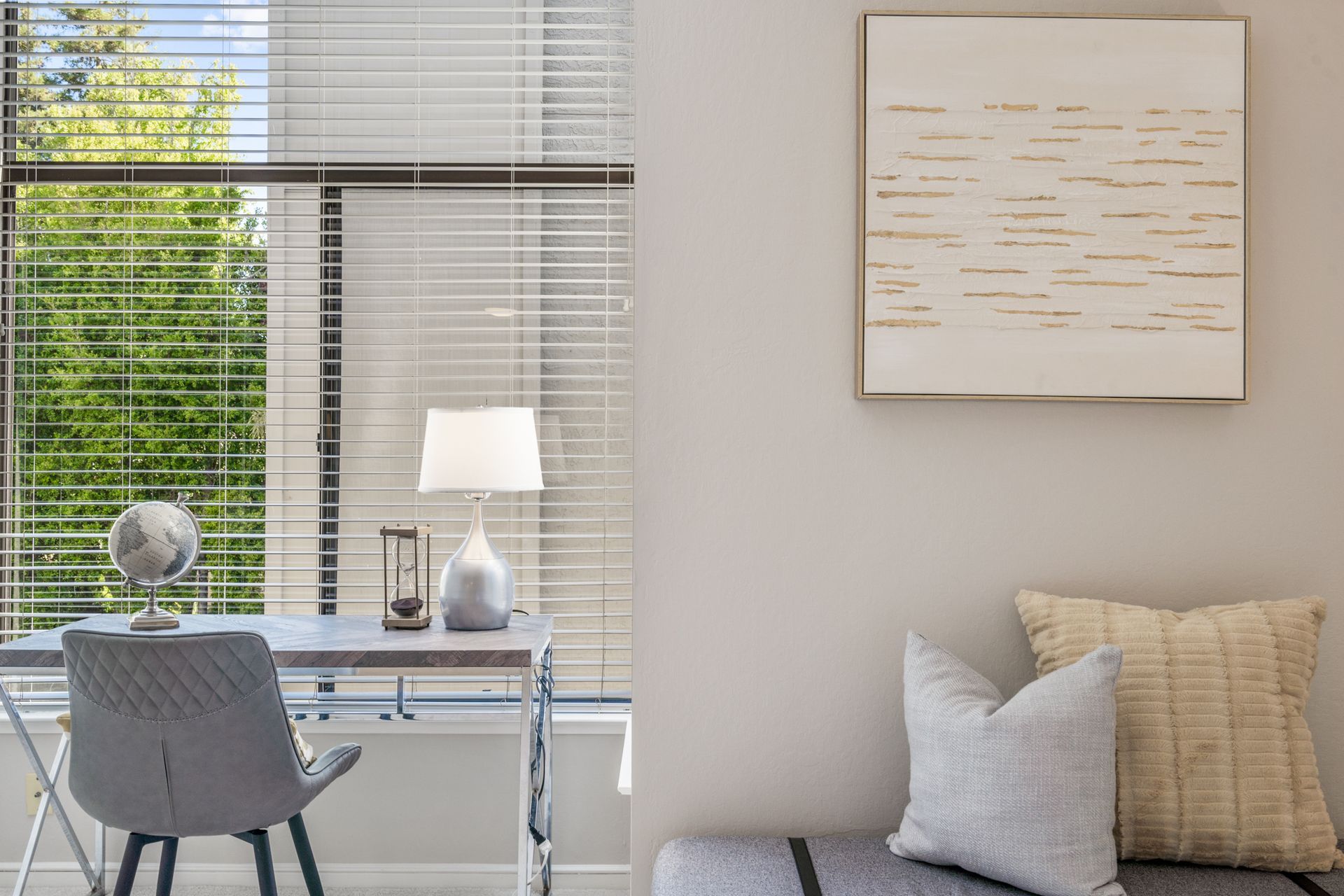 A living room with a desk and chair and a painting on the wall