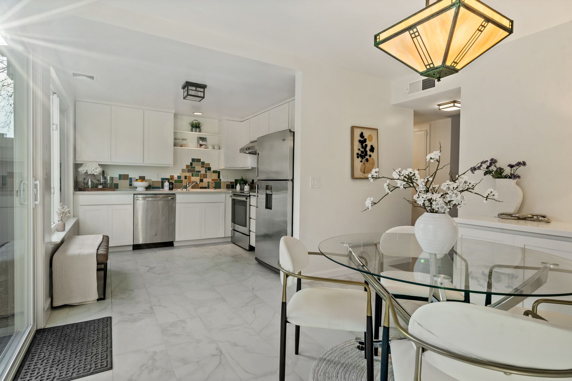 A kitchen and dining room with a glass table and chairs