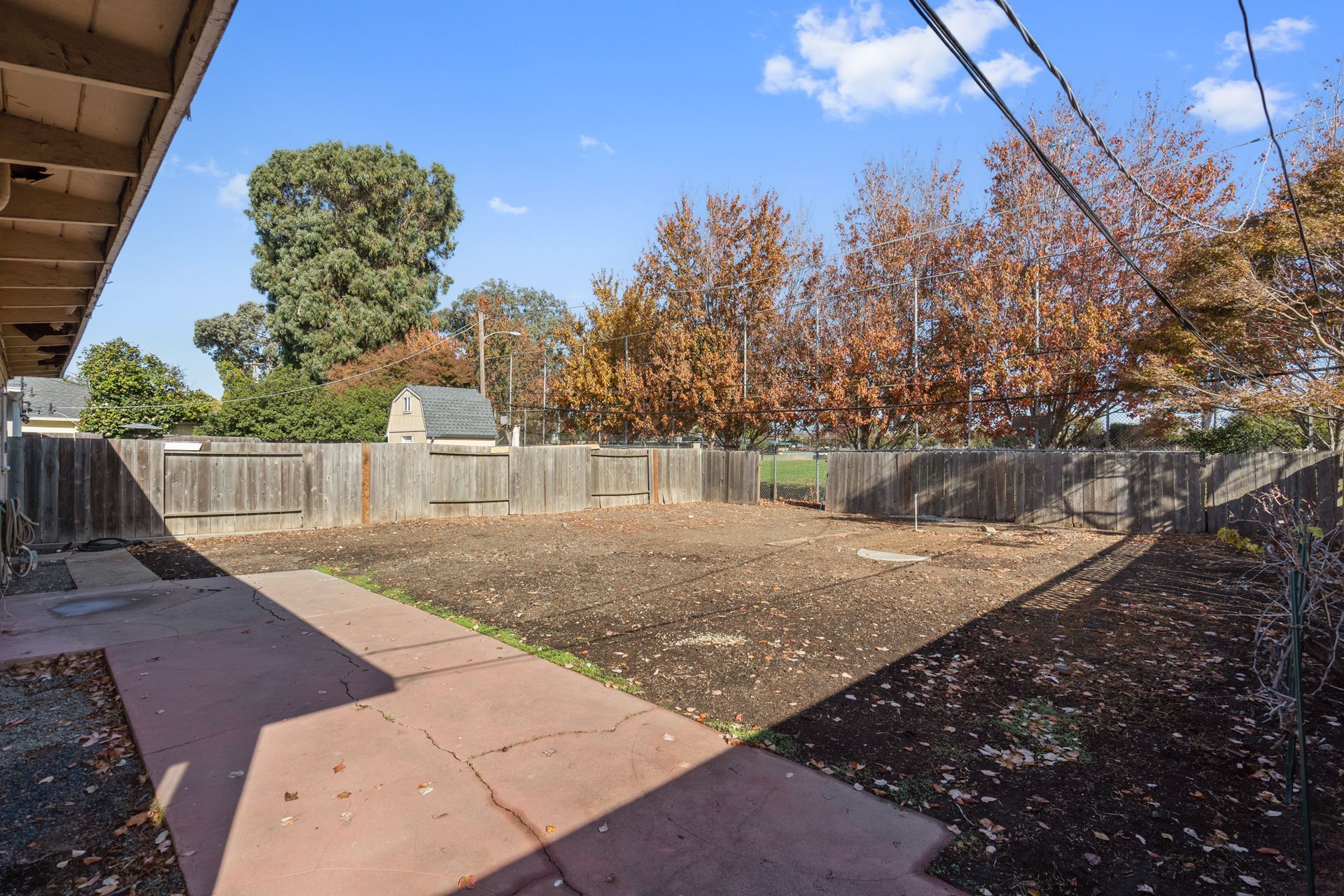The backyard of a house with a fence and trees in the background.